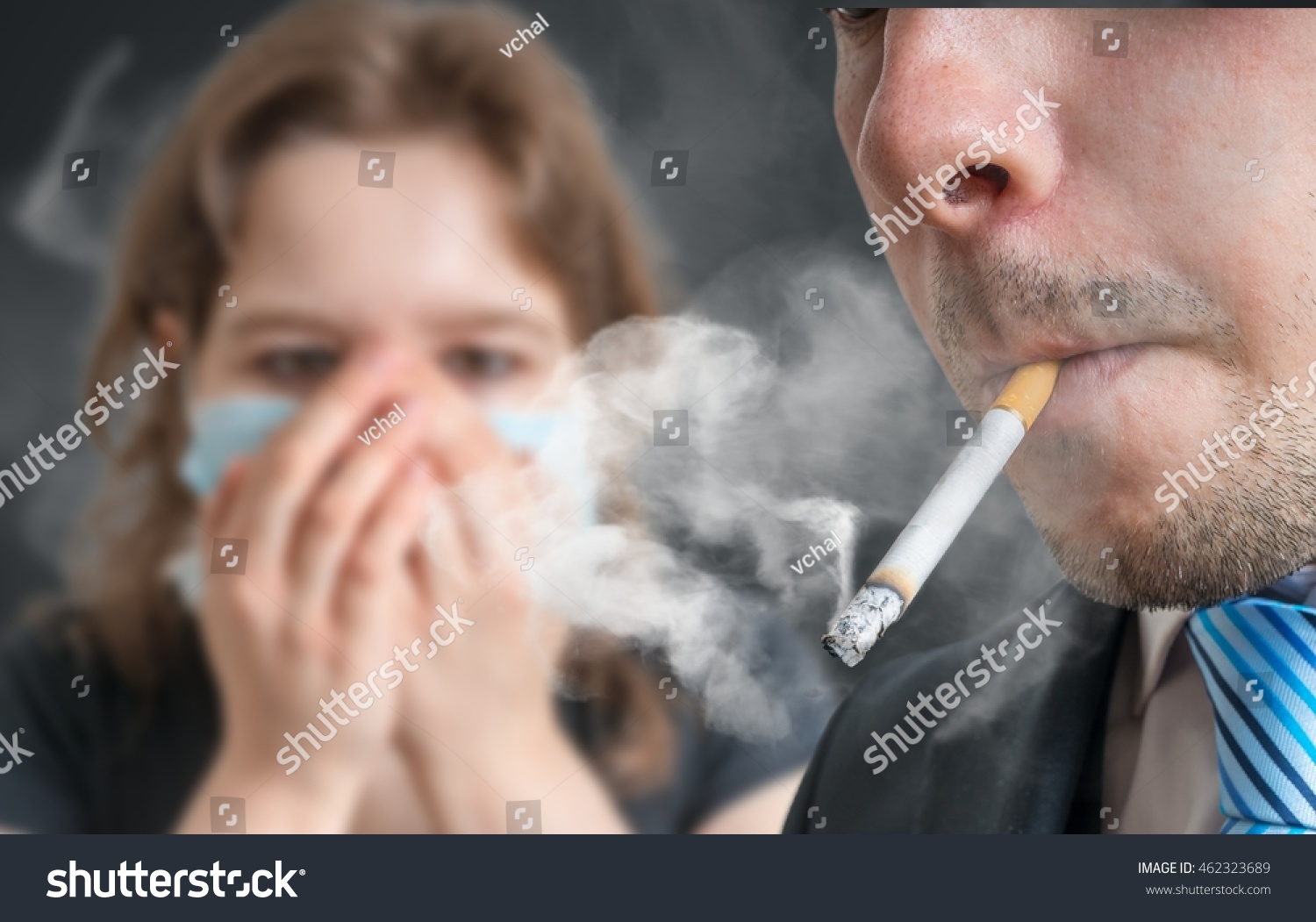 Passive smoking concept. Man is smoking cigarette and woman is covering her face. A lot of smoke around. #462323689
