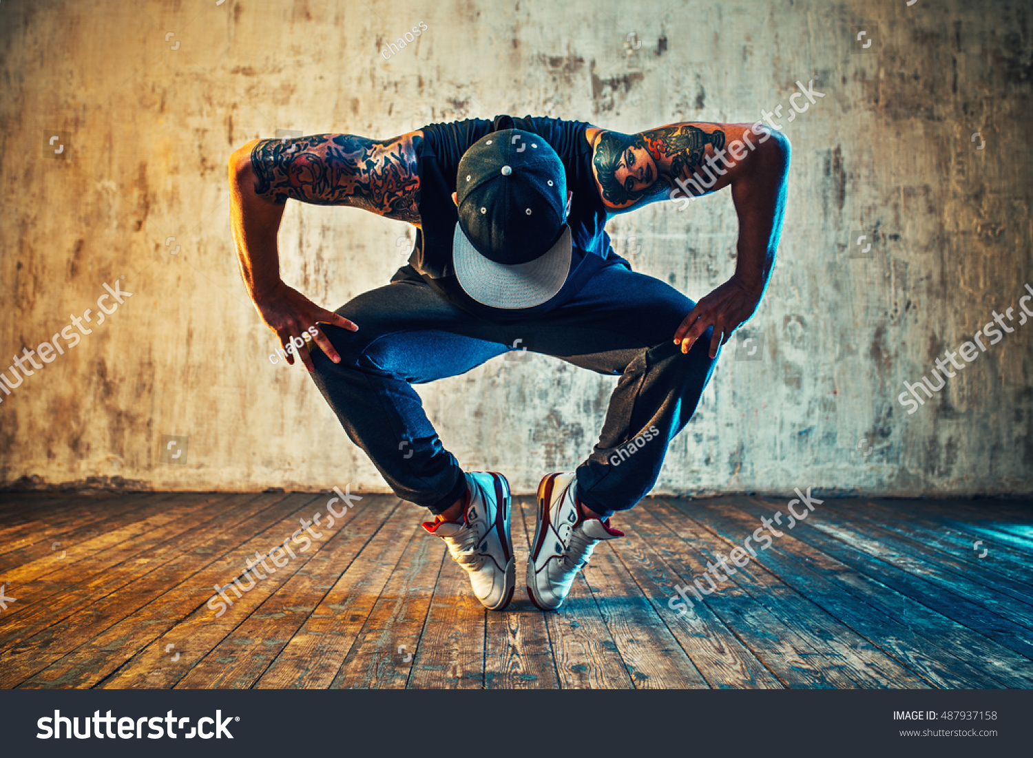 Young man break dancing on wall background. Blue and yellow colors tint. Tattoo on body. #487937158