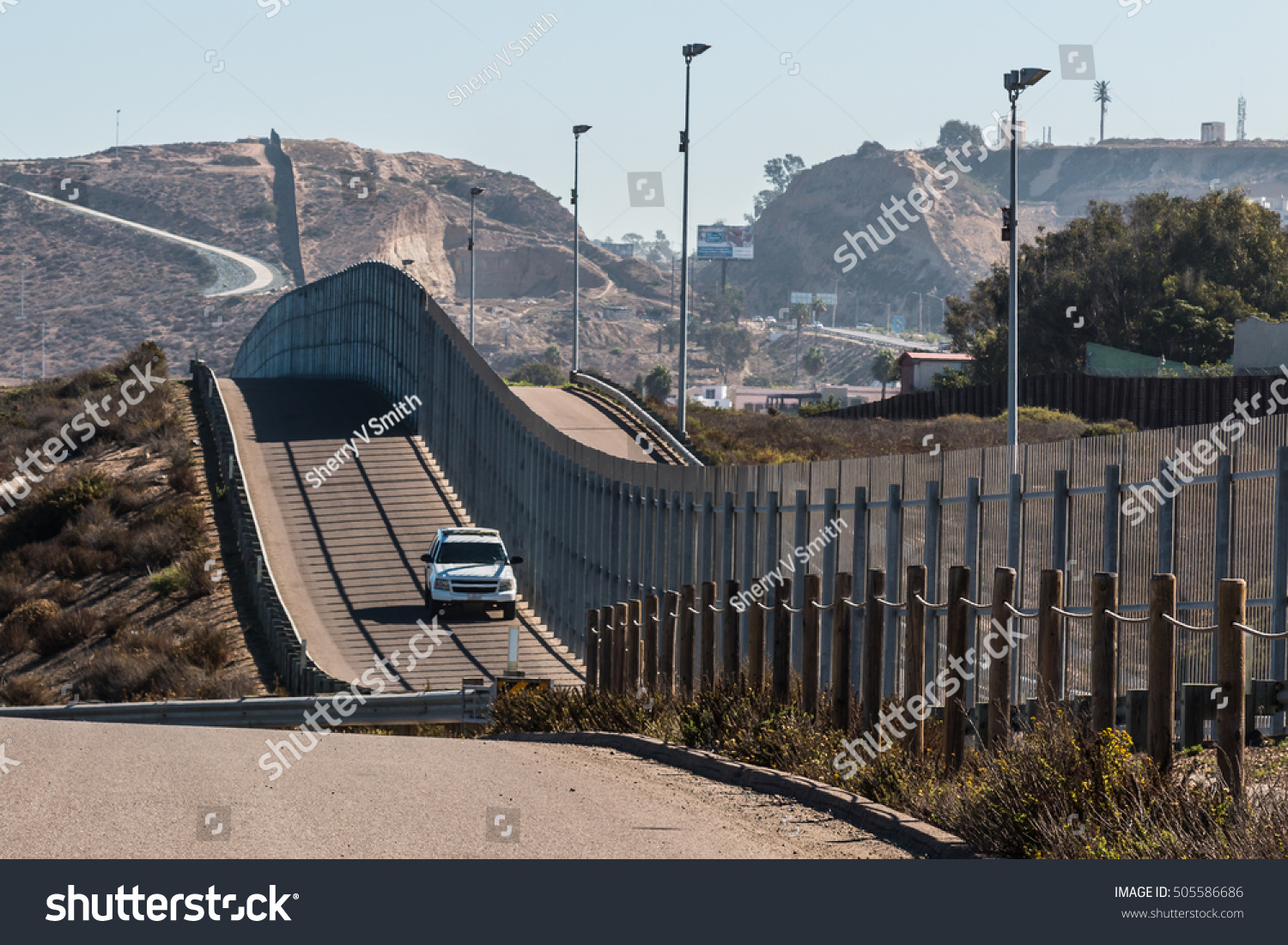 Border Patrol vehicle patrolling along the fence of the international border between San Diego, California and Tijuana, Mexico #505586686