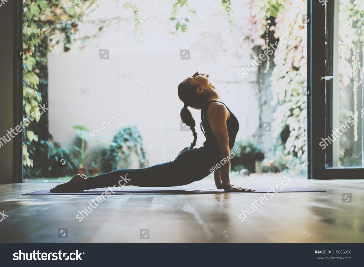 Portrait of gorgeous young woman practicing yoga indoor. Beautiful girl practice cobra asana in class.Calmness and relax, female happiness.Horizontal, blurred background #515885956