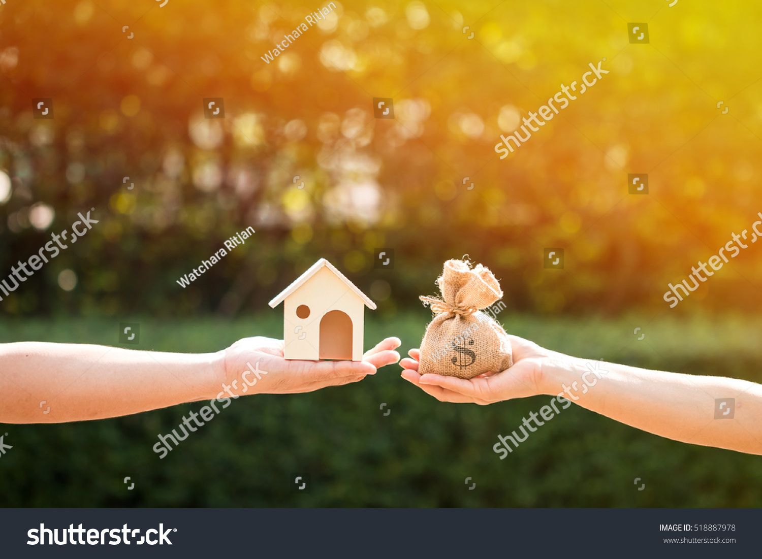 Loans for real estate concept, a man and a women hand holding a money bag and  a model home put together in the public park. #518887978