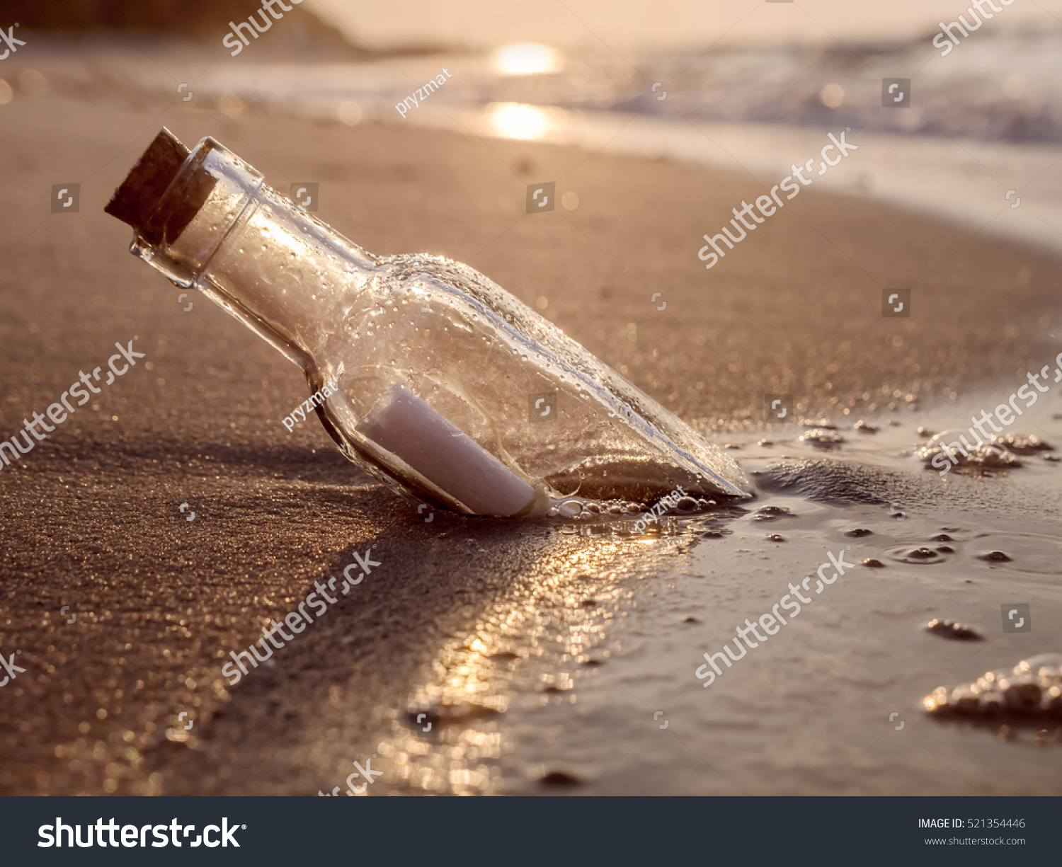 Message in the bottle washed ashore against the Sun setting down #521354446