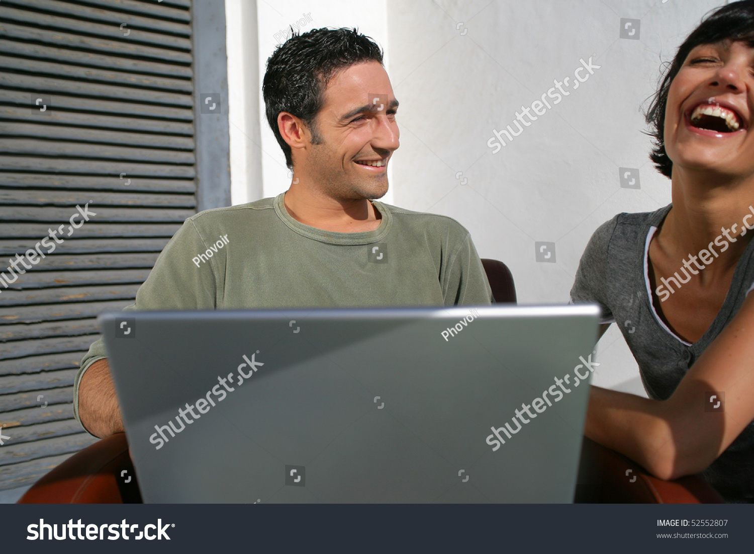 Happy couple laughing in front of a laptop computer #52552807