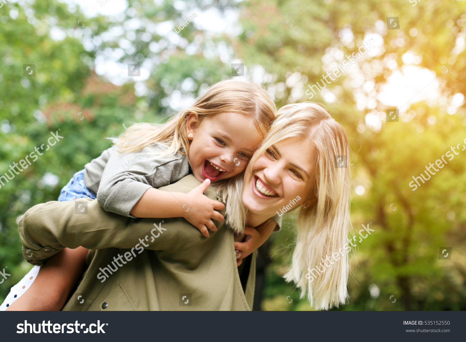 Cute young daughter on a piggy back ride with her mother. #535152550