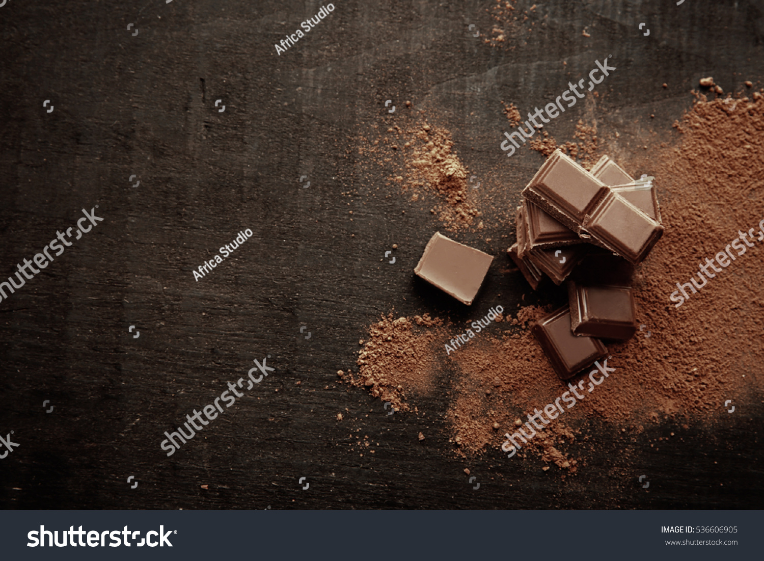 Broken chocolate pieces and cocoa powder on wooden background #536606905