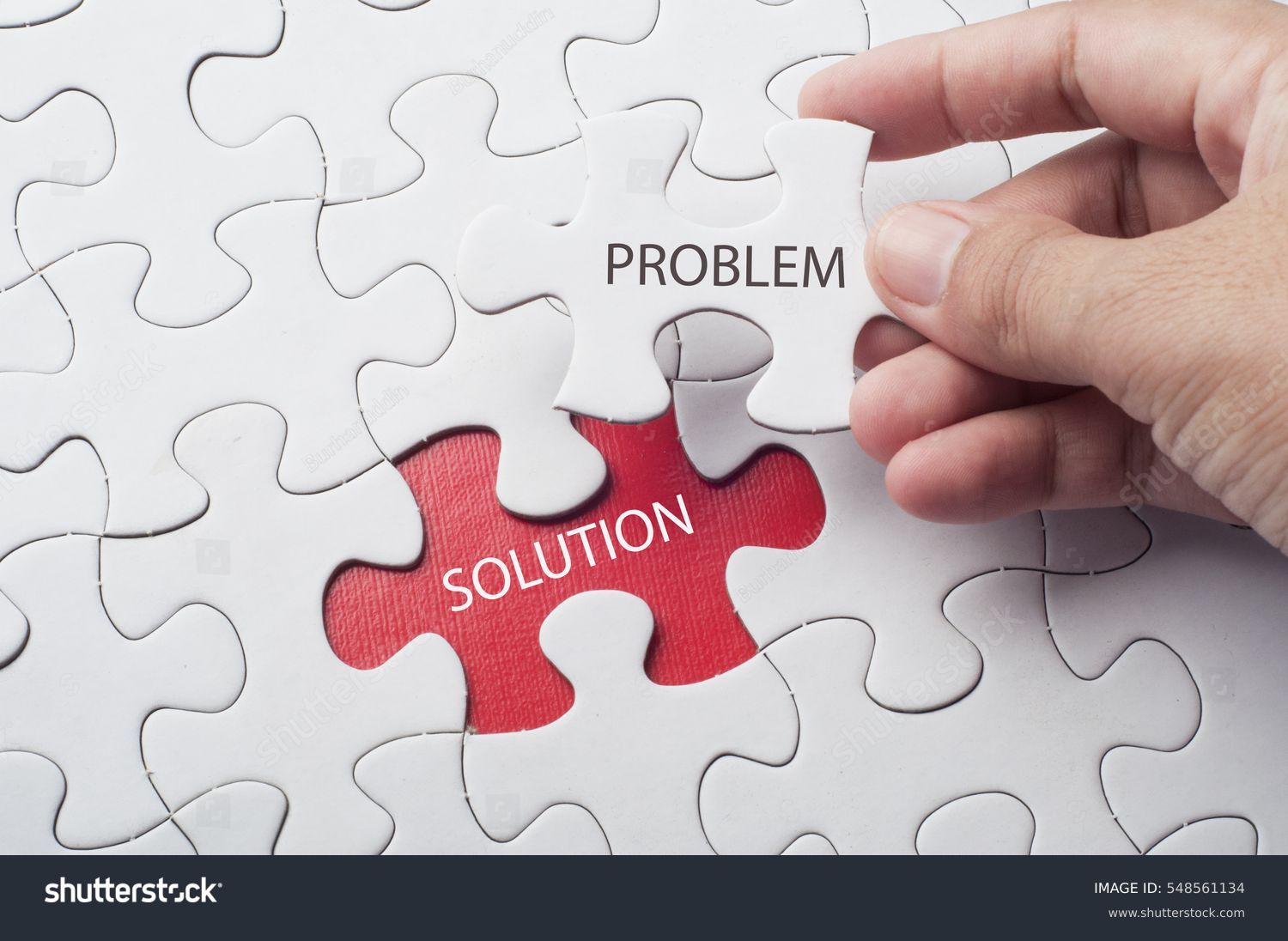 Hand holding piece of jigsaw puzzle with word problem & solution. #548561134