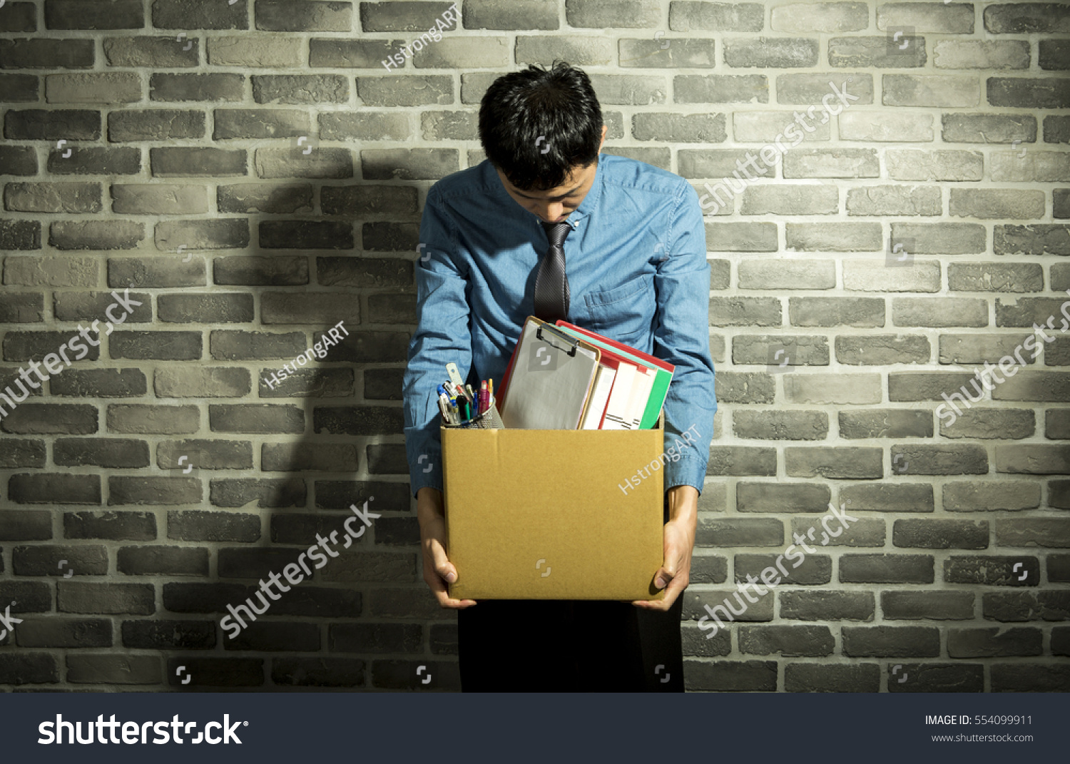 depressed man holding box in his hands, with office supplies inside, wall background #554099911