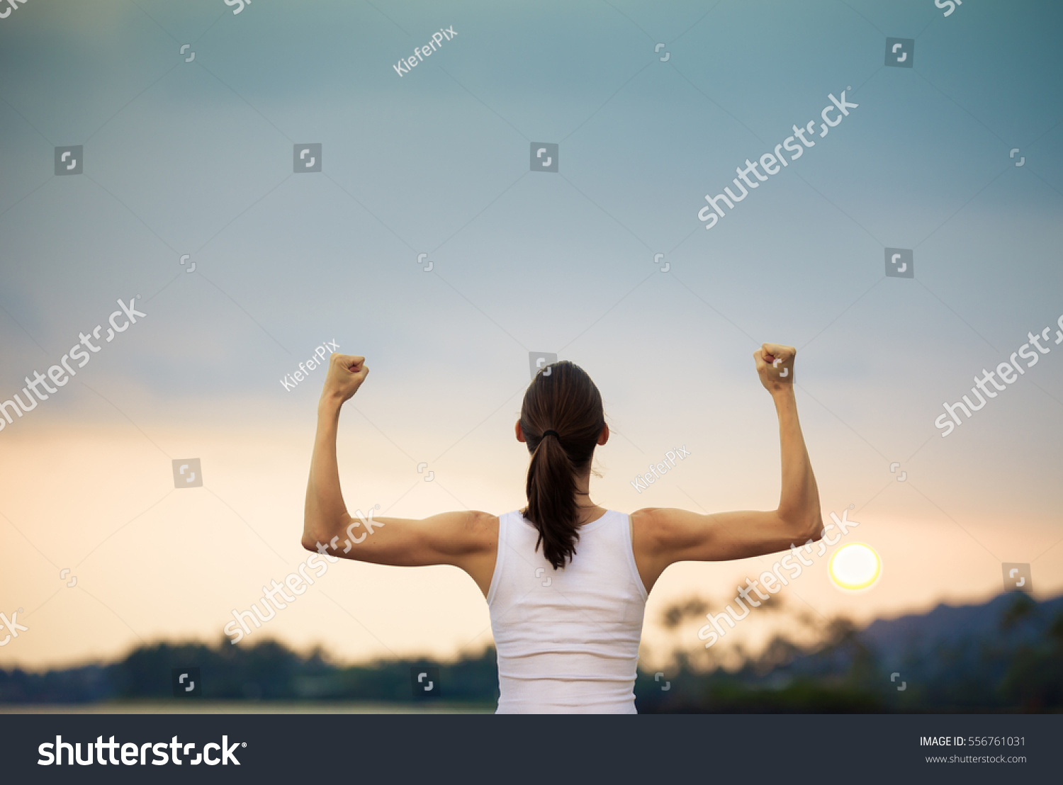 Woman power! Strong and confident woman flexing her muscles.  #556761031