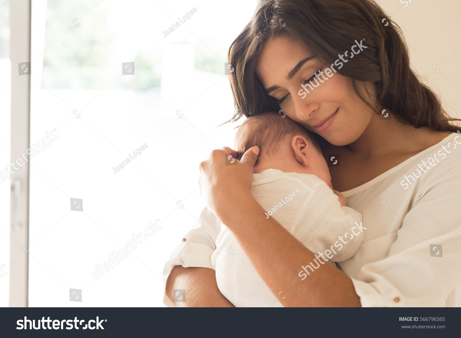 Pretty woman holding a newborn baby in her arms #566796565