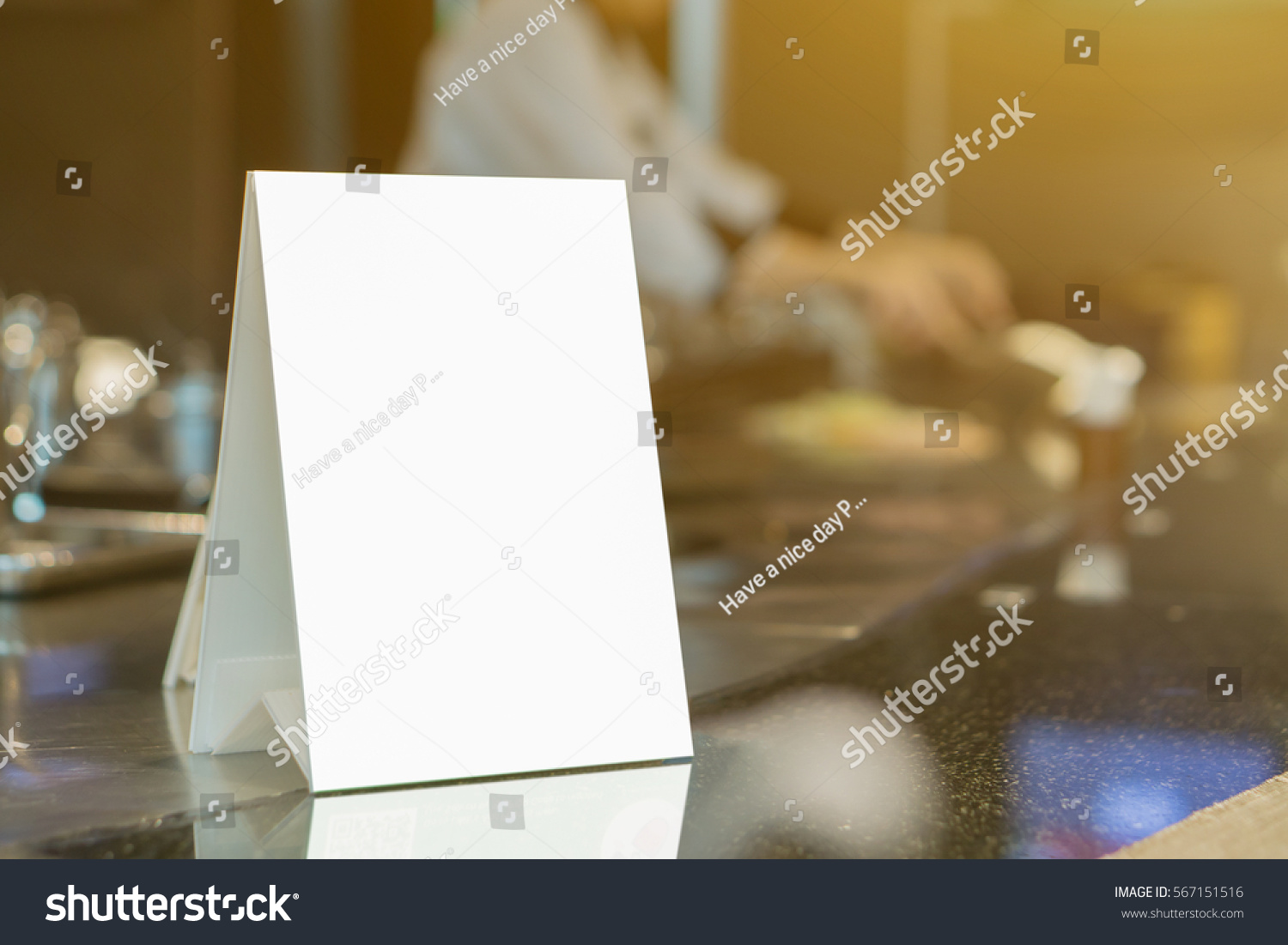 Mock up Menu frame on Table in Bar restaurant ,Stand for booklets with white sheets of paper acrylic tent card on cafeteria blurred ,Chef cooking in background.  #567151516