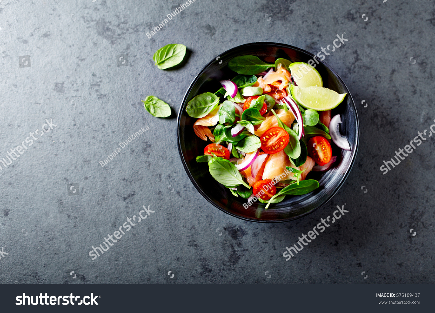Salmon Salad with spinach, cherry tomatoes, corn salad, baby spinach, fresh mint and basil. Home made food. Concept for a tasty and healthy meal. Dark stone background. Top view. Copy space. #575189437