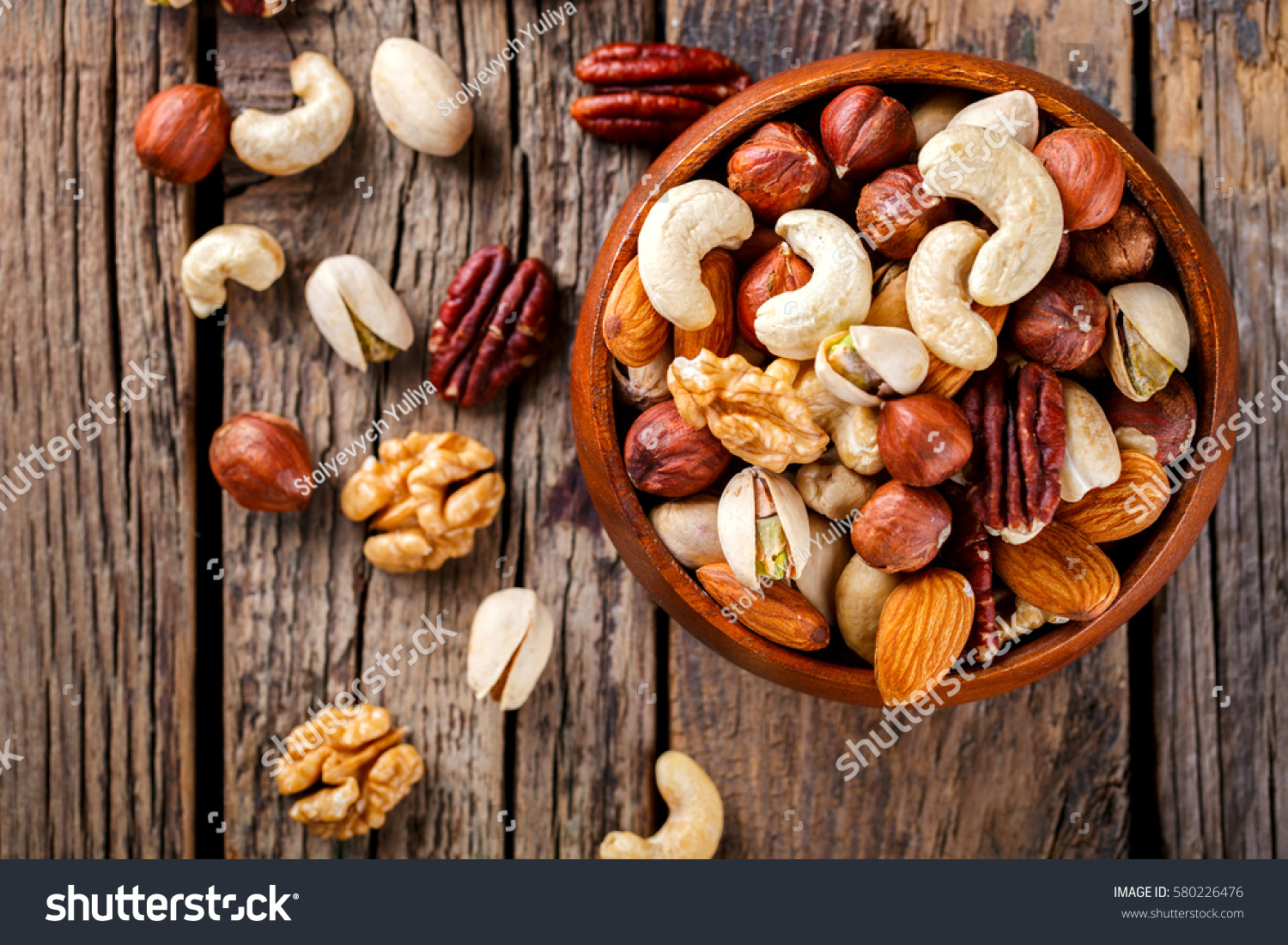 Nuts Mixed in a wooden plate.Assortment, Walnuts,Pecan,Almonds,Hazelnuts,Cashews,Pistachios.Concept of Healthy Eating.Vegetarian.selective focus. #580226476