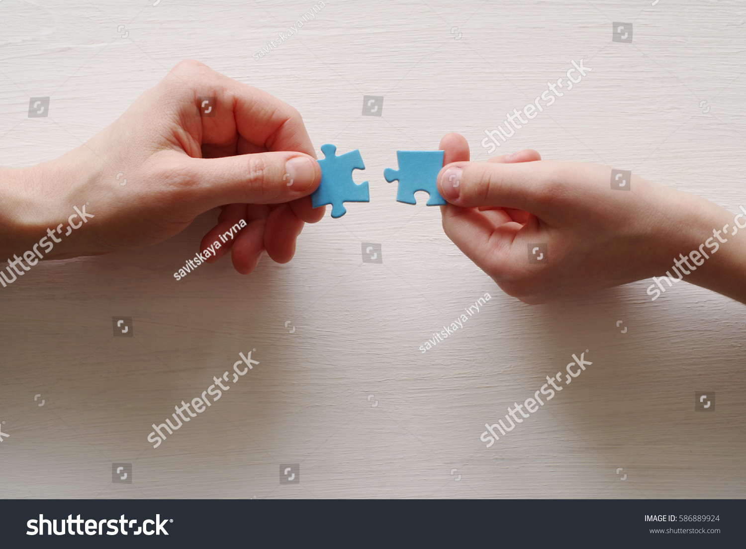 Puzzles. Hand of the child and hand of mother fold puzzle, closeup, top view #586889924