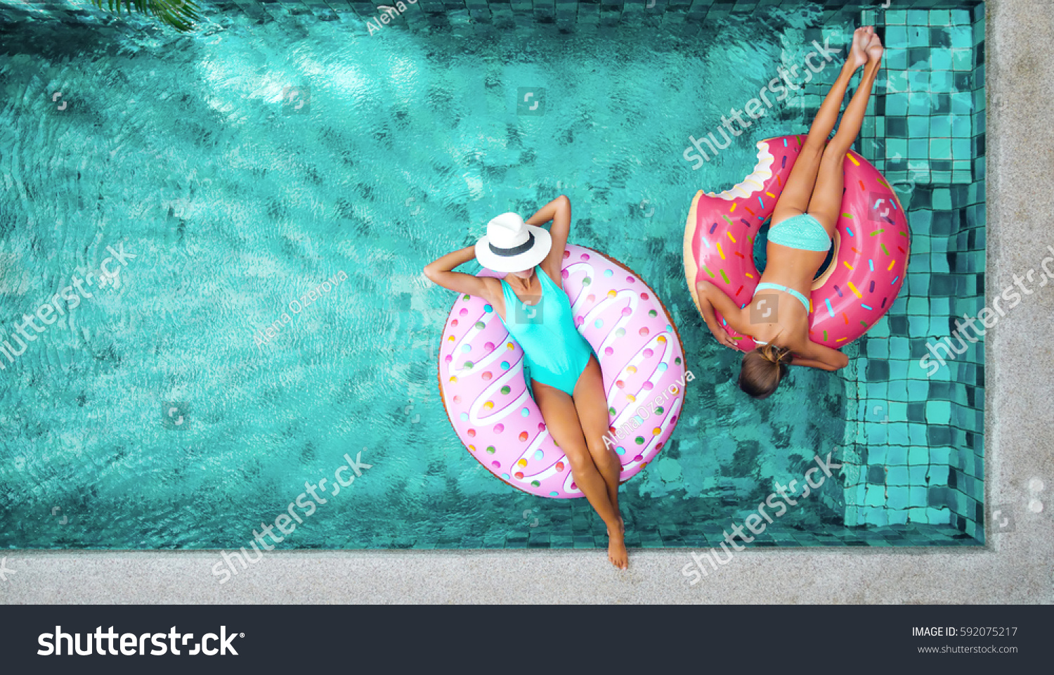 Zwei Personen (Mutter und Kind) entspannen auf Donut Lilo im Pool in der privaten Villa. Sommerurlaub idyllisch. Hohe Sicht von oben. #592075217