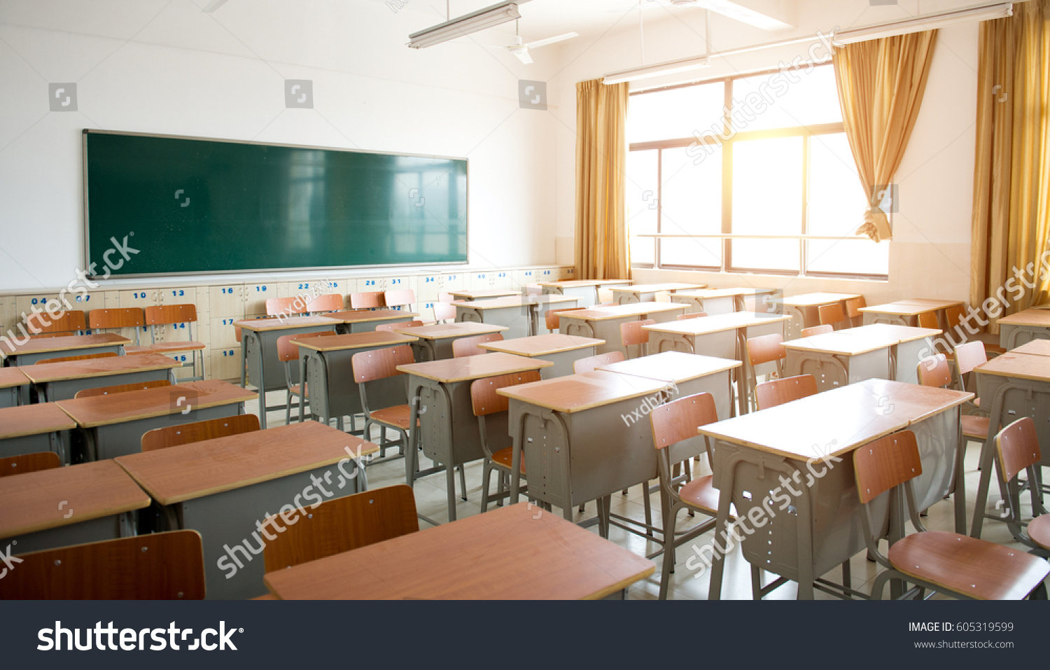 Empty classroom with chairs, desks and chalkboard. #605319599
