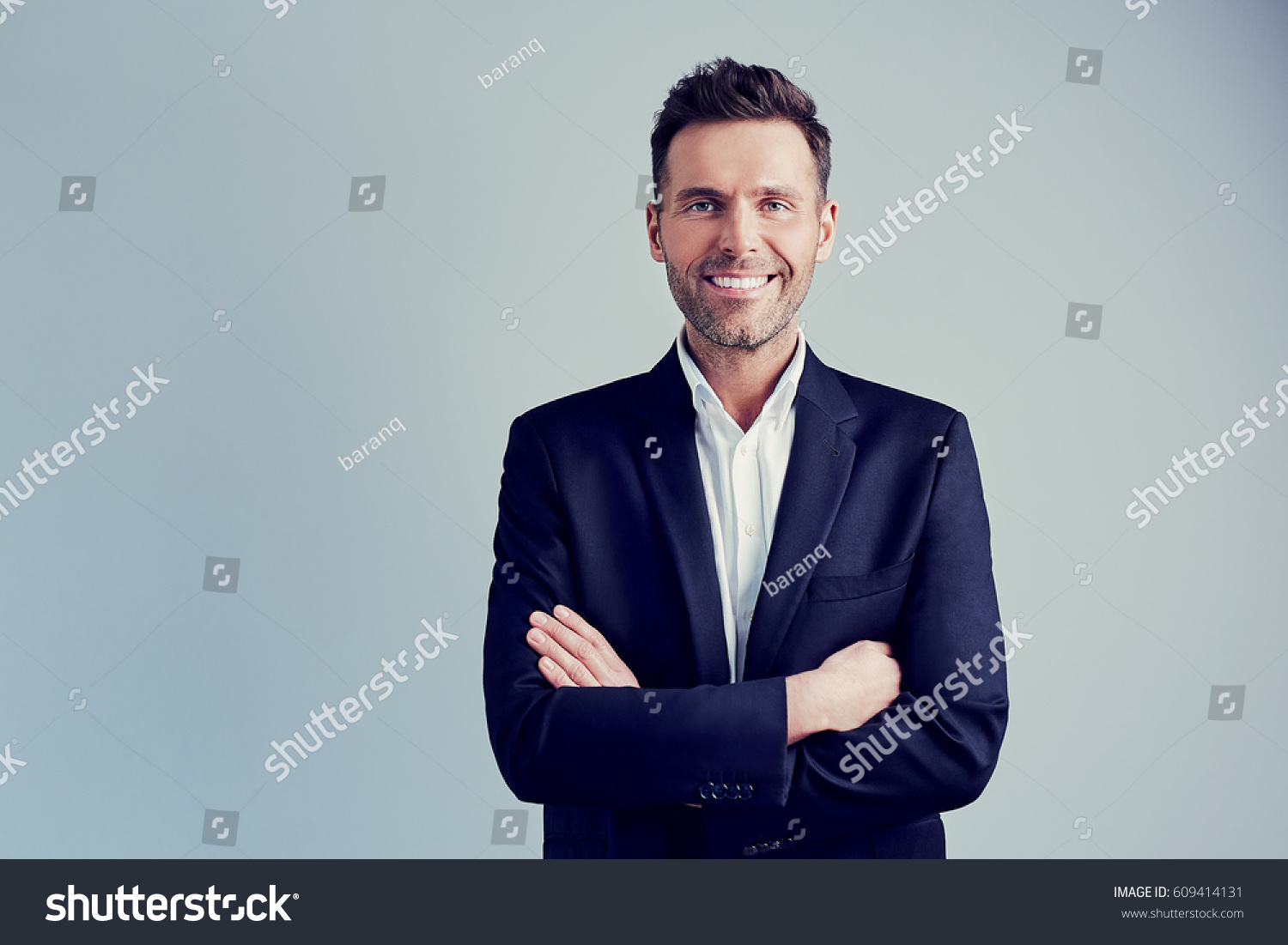 Happy businessman isolated - handsome man standing with crossed arms #609414131