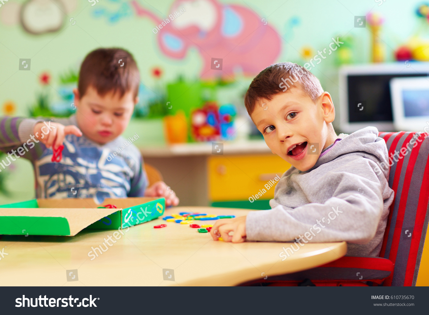 cute kids with special needs playing with developing toys while sitting at the desk in daycare center #610735670