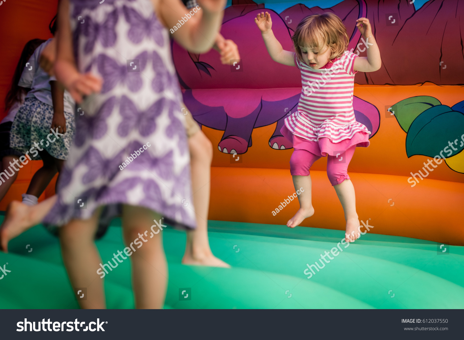 Cute little girl jumping inside the inflatable bouncy castle #612037550