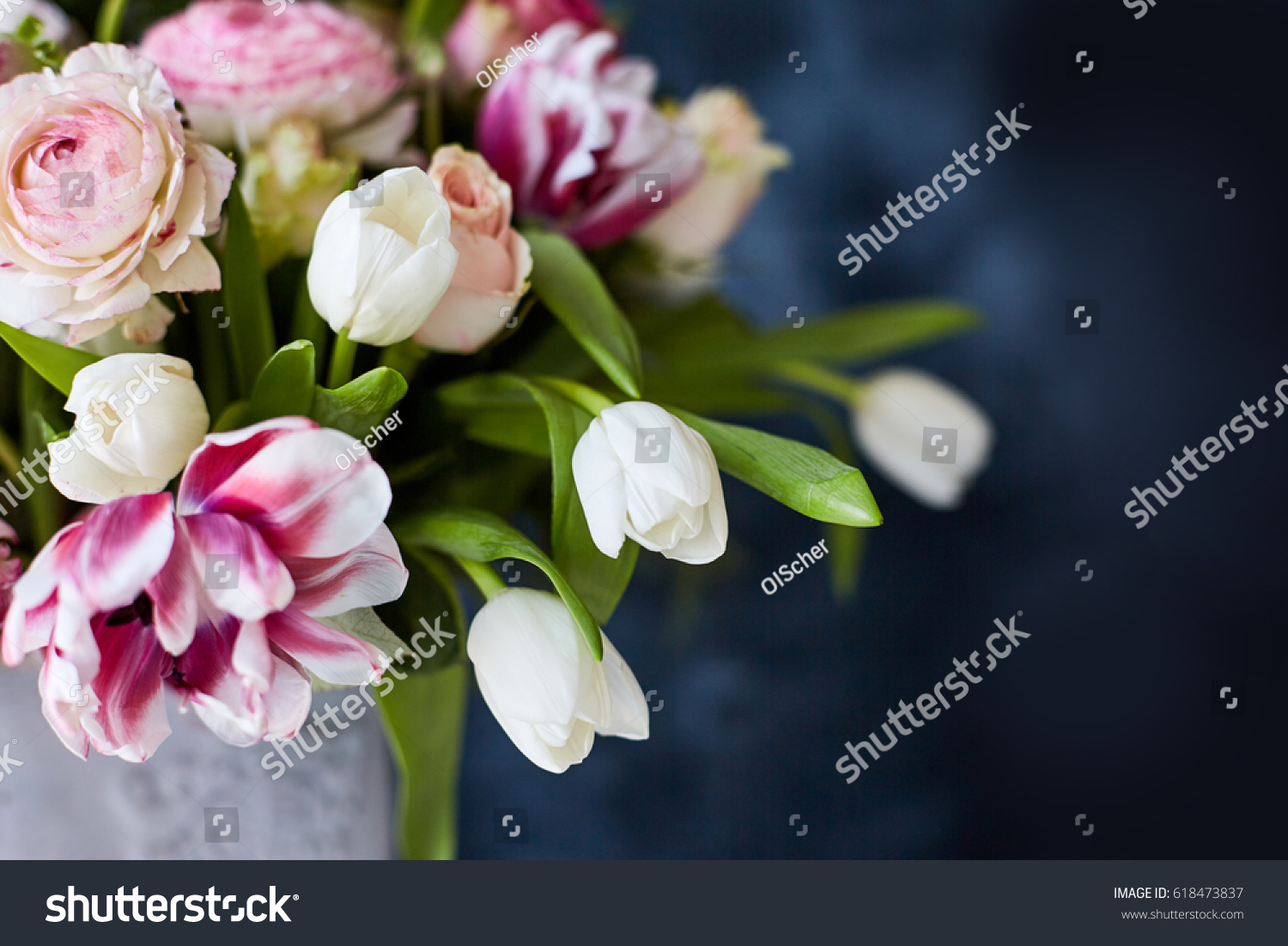 
Flower arrangement with tulips and ranunculus on a white wooden floor. Spring flower arrangement in a vase #618473837