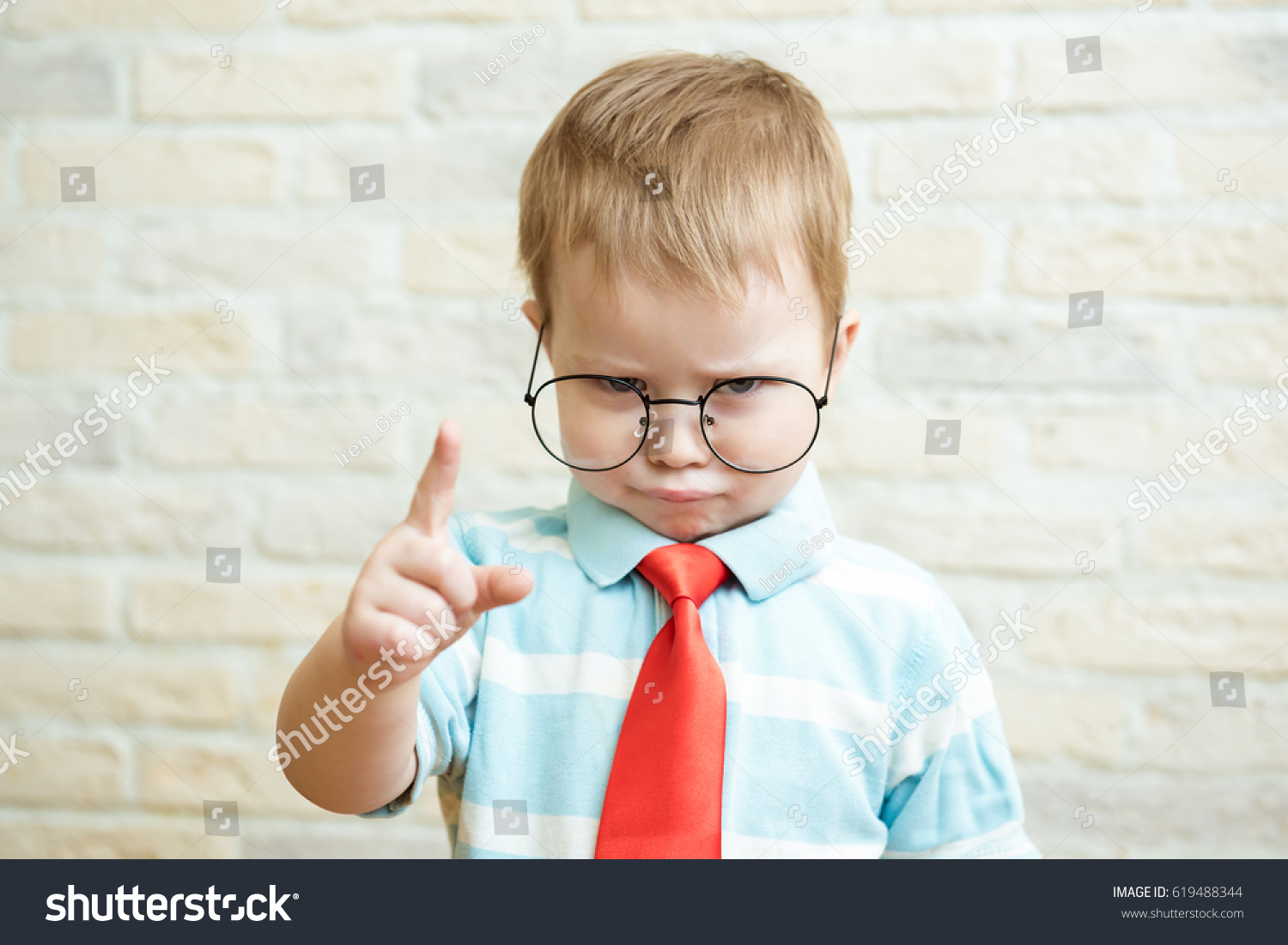 Serious boy standing with a finger in big glasses. The concept of the evil boss. #619488344