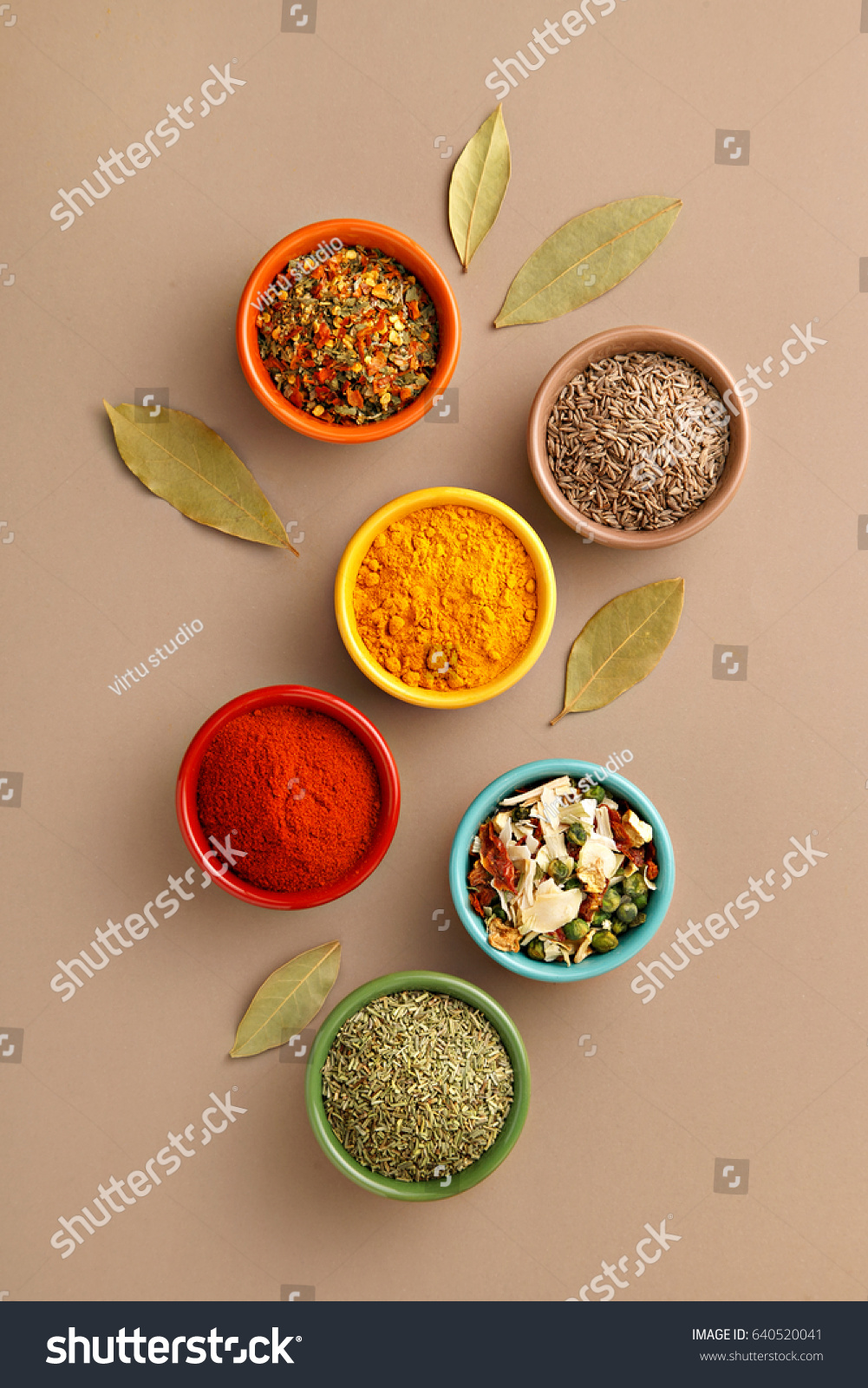 Spices in colorful bowls viewed from above. Various seasonings on a dark background. Italian mix, cumin, chili pepper, curry powder, Himalayan salt, pepper, garlic, cinnamon, dried tomato. Top view #640520041