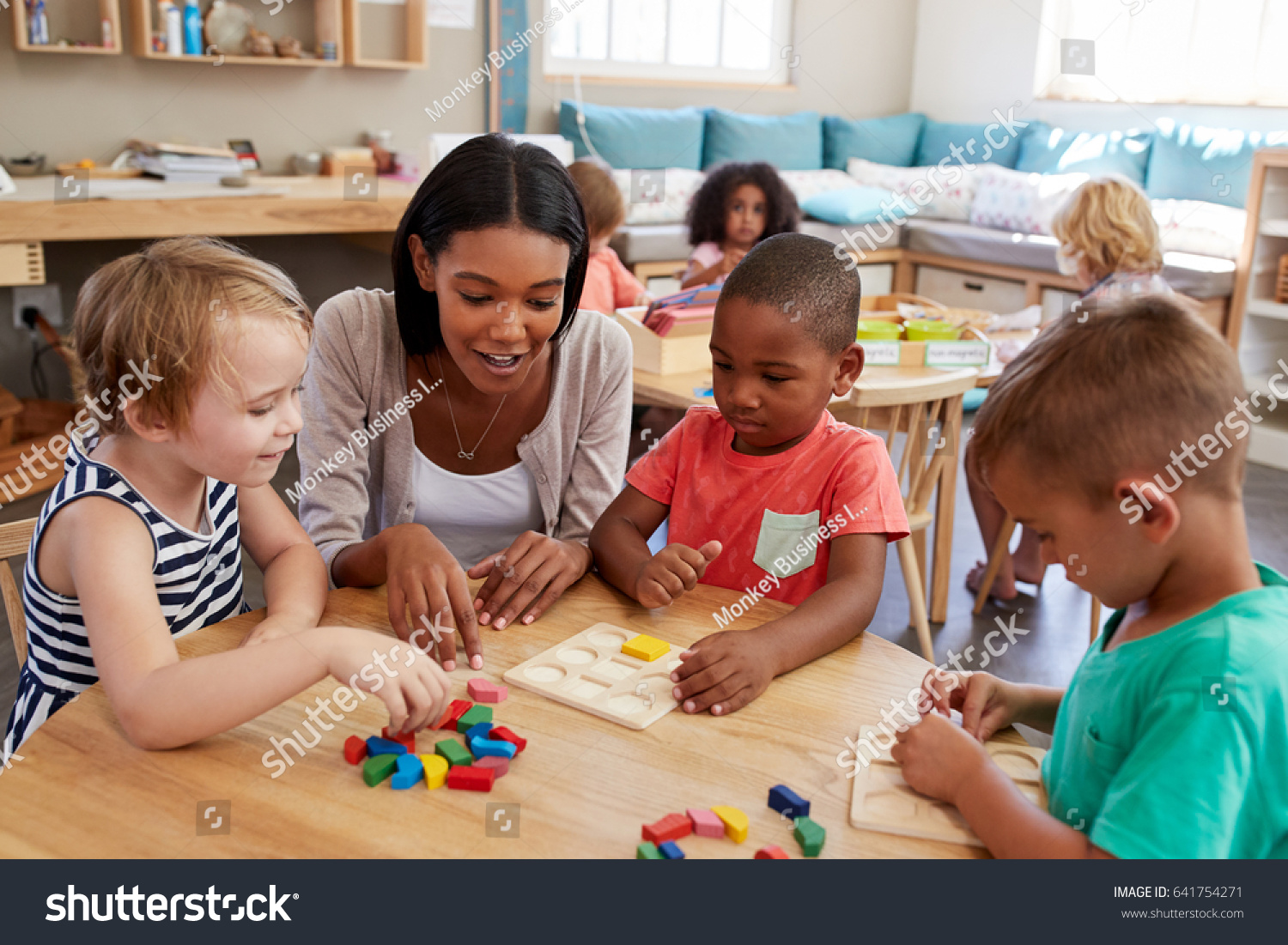 Teacher And Pupils Using Wooden Shapes In Montessori School #641754271
