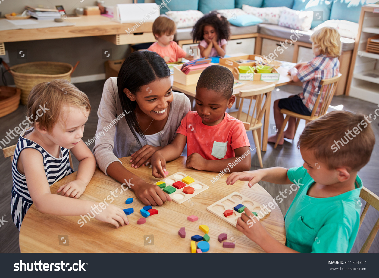 Teacher And Pupils Using Wooden Shapes In Montessori School #641754352