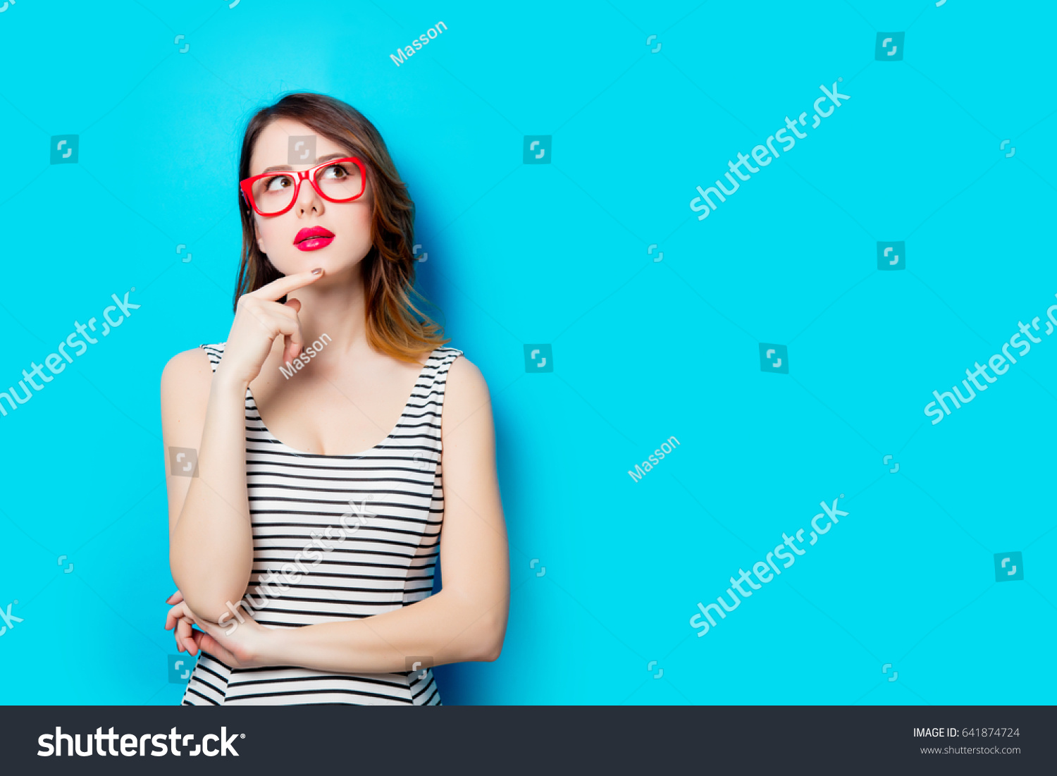 portrait of beautiful young woman in glasses on the wonderful blue studio background #641874724