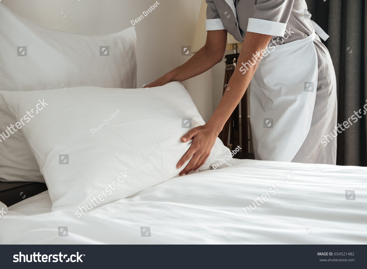 Cropped image of a female chambermaid making bed in hotel room #654521482