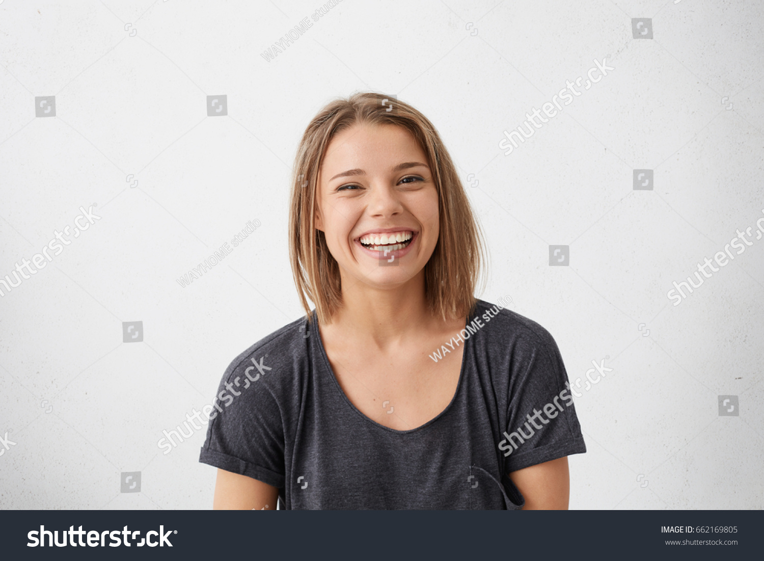 Attractive woman with short fair hair being very glad smiling with broad smile showing her perfect teeth having fun indoors. Joyful excited cheery femlae rejoicing after being proposed to marry #662169805