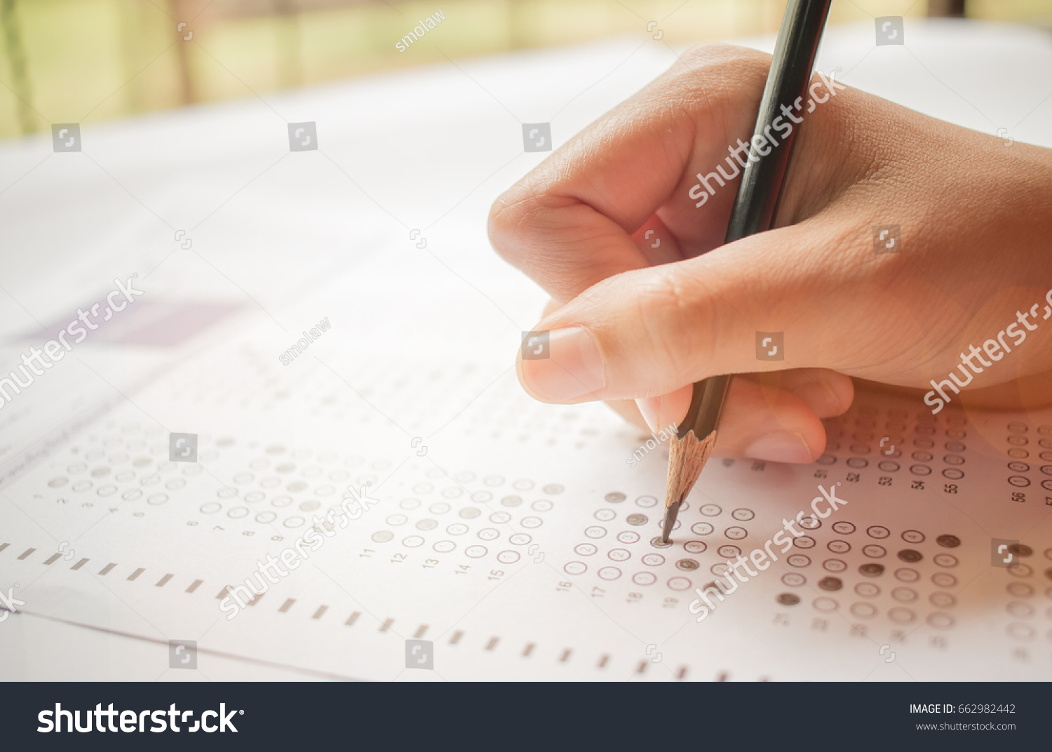 hand student testing in exercise and taking fill in exam carbon paper computer sheet with pencil at school test room, education concept #662982442