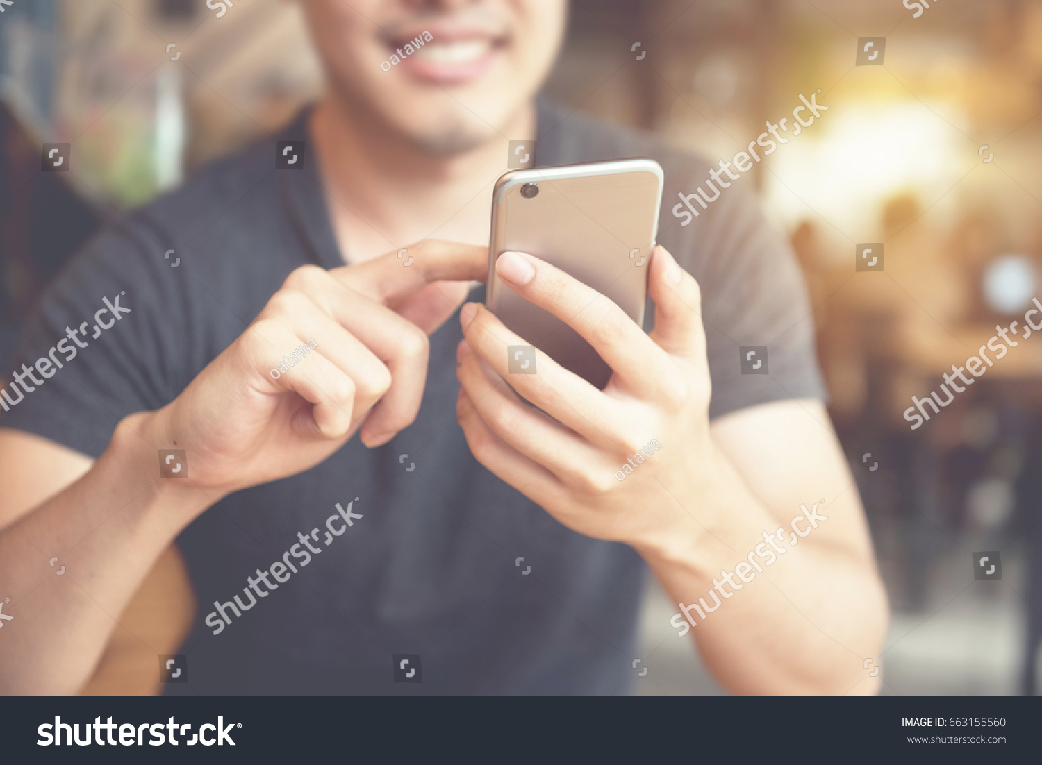 Happy man using smartphone at modern coffee shop, he chatting Online Messaging on mobile phone. #663155560