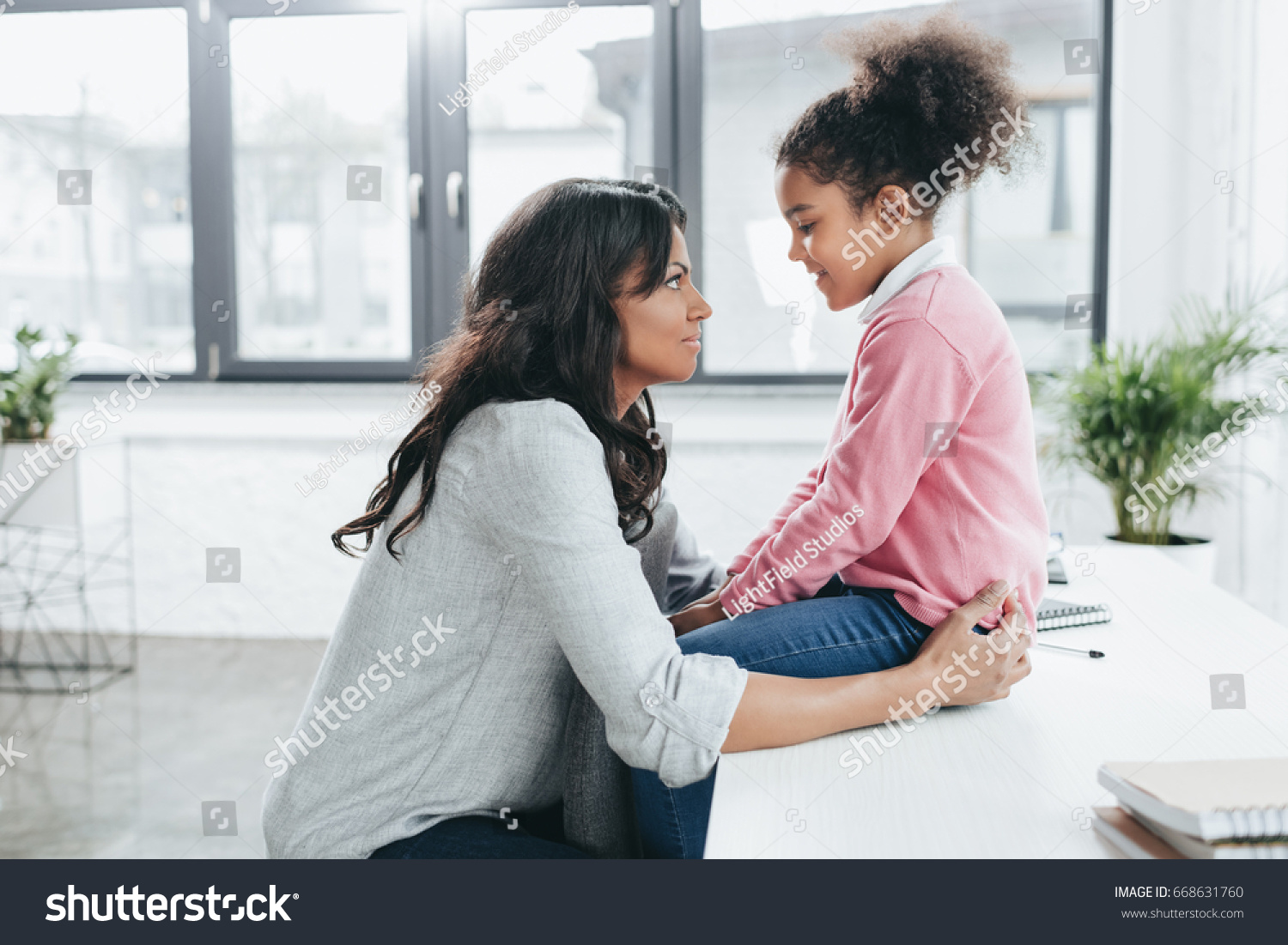side view of african american mother talking with her daughter indoors #668631760