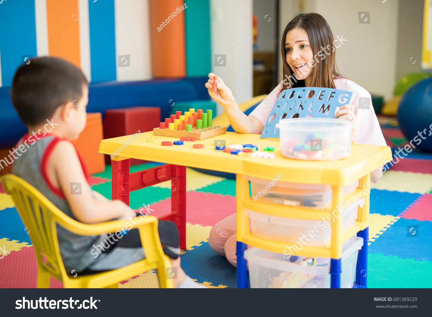 Cute Hispanic language therapist working with a kid in a special needs school #681369220