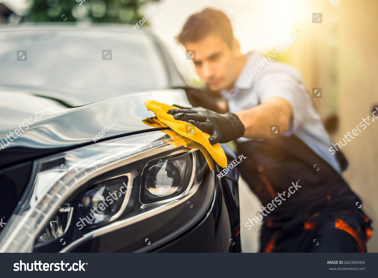 Car detailing - the man holds the microfiber in hand and polishes the car. Selective focus. #682966966