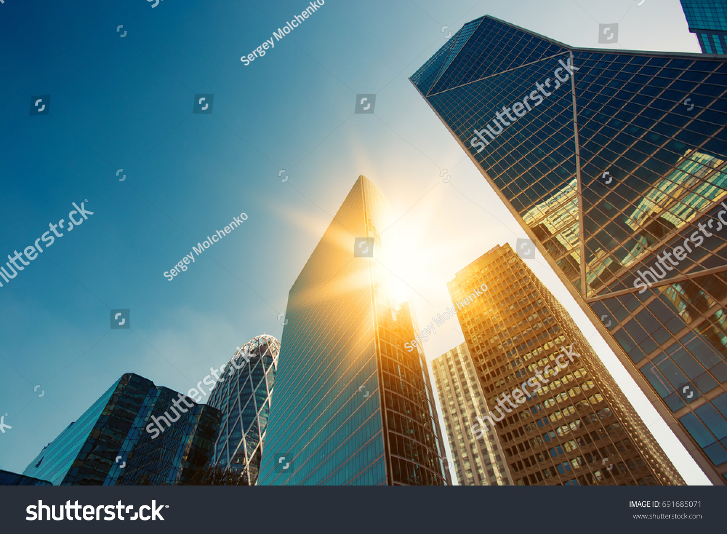 Mrakodrap skleněné fasády za jasného slunečného dne se slunečními paprsky na modré obloze. Moderní budovy v Paříži obchodní čtvrti La Defense. Ekonomika, finance, koncepce podnikání. Pohled zdola nahoru #691685071