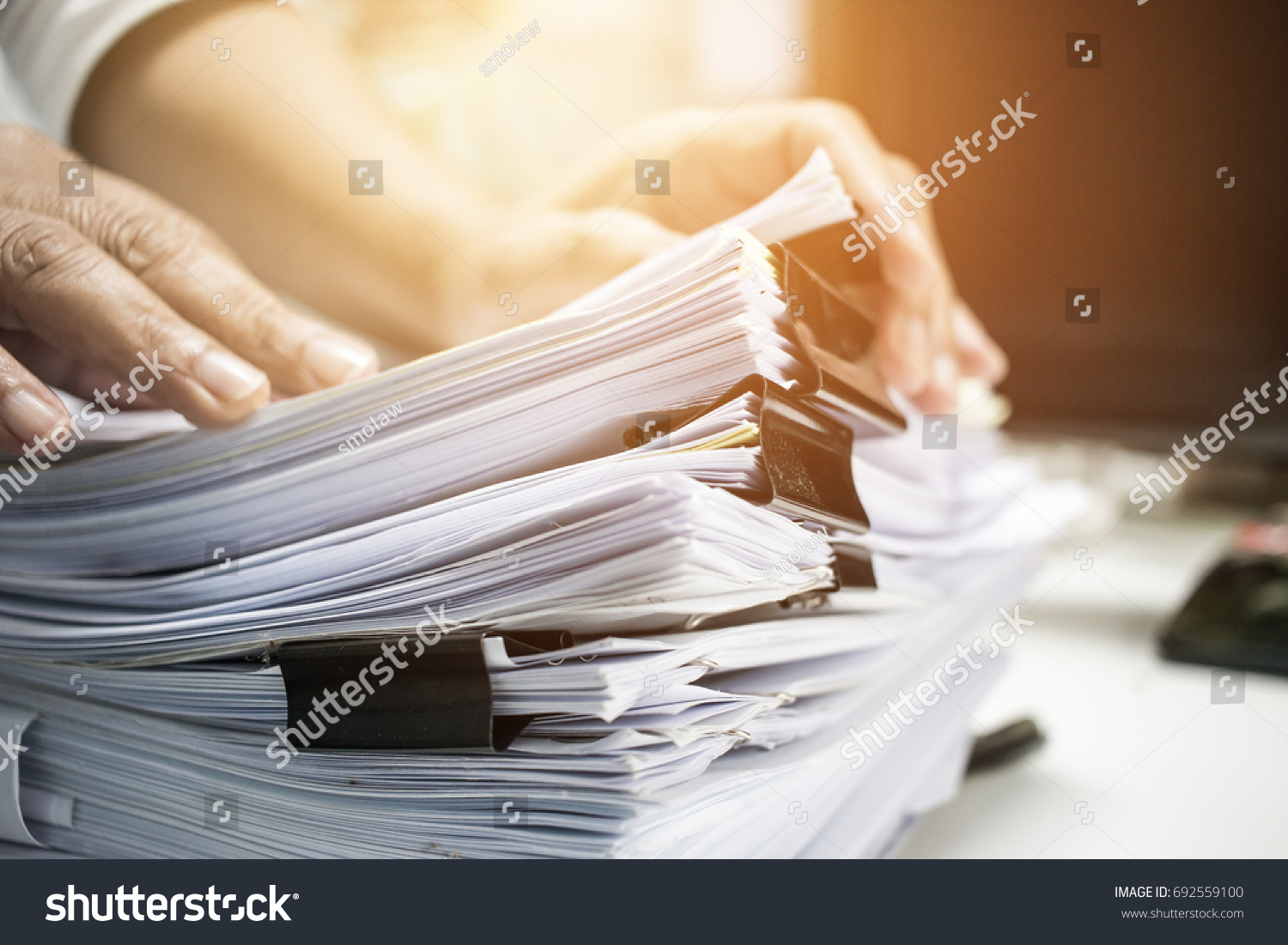 Work from Home, Businessman hands working in Stacks of paper files for searching information on work desk home office, business report papers,piles of unfinished documents achieves with clips indoor. #692559100