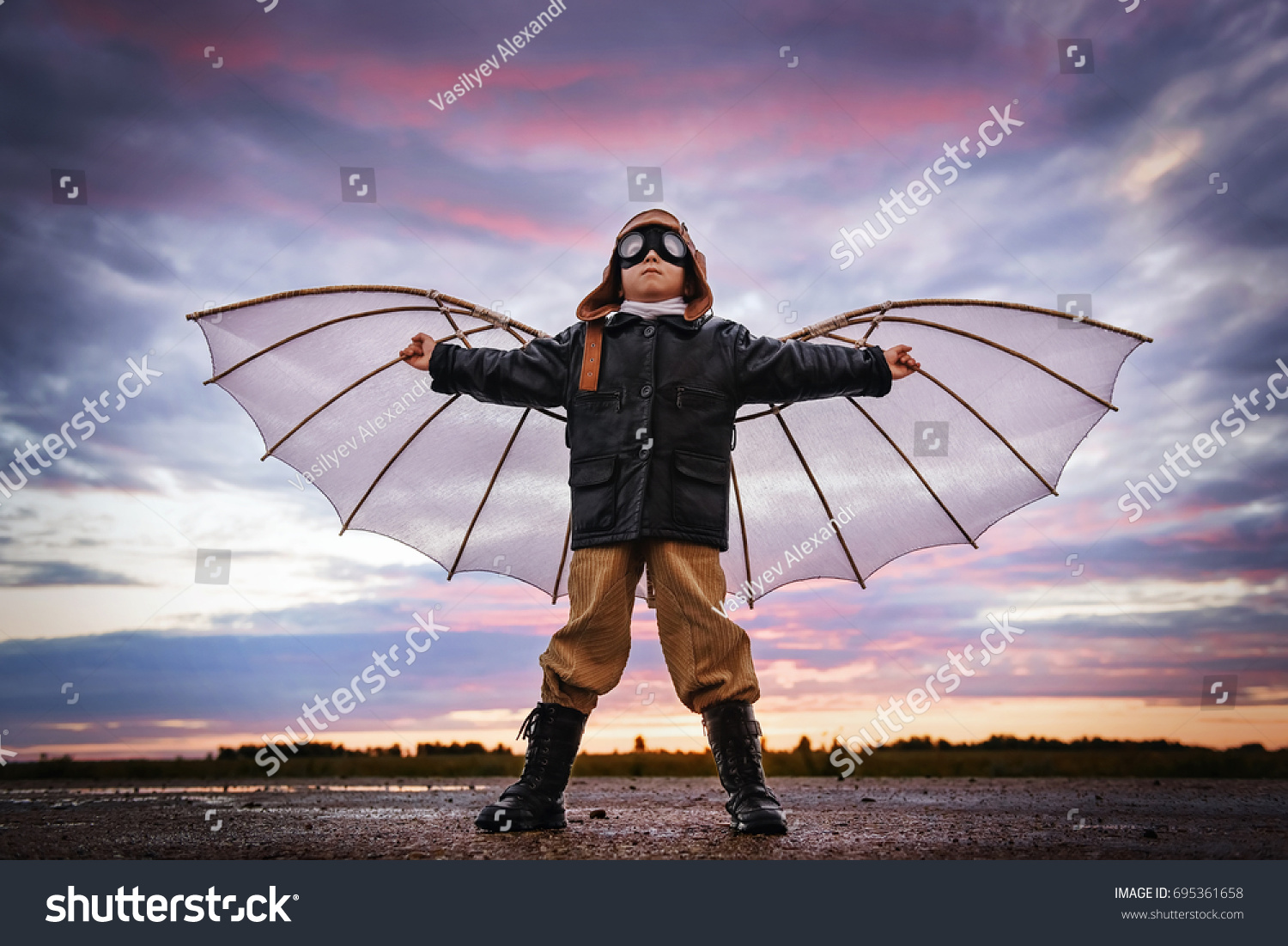 Boy with wings at sunset imagines himself a pilot and dreams of flying #695361658