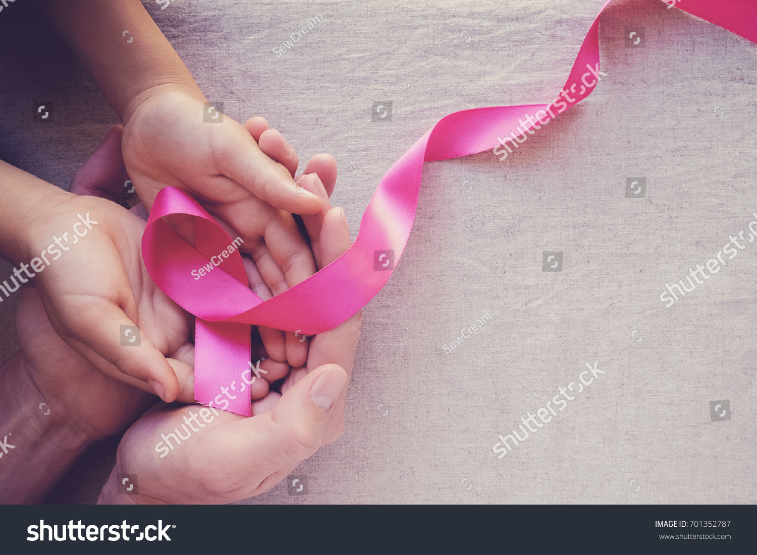 Adult and child hands holding pink ribbons, Breast cancer awareness, abdominal cancer awareness and October Pink day background, world cancer day #701352787