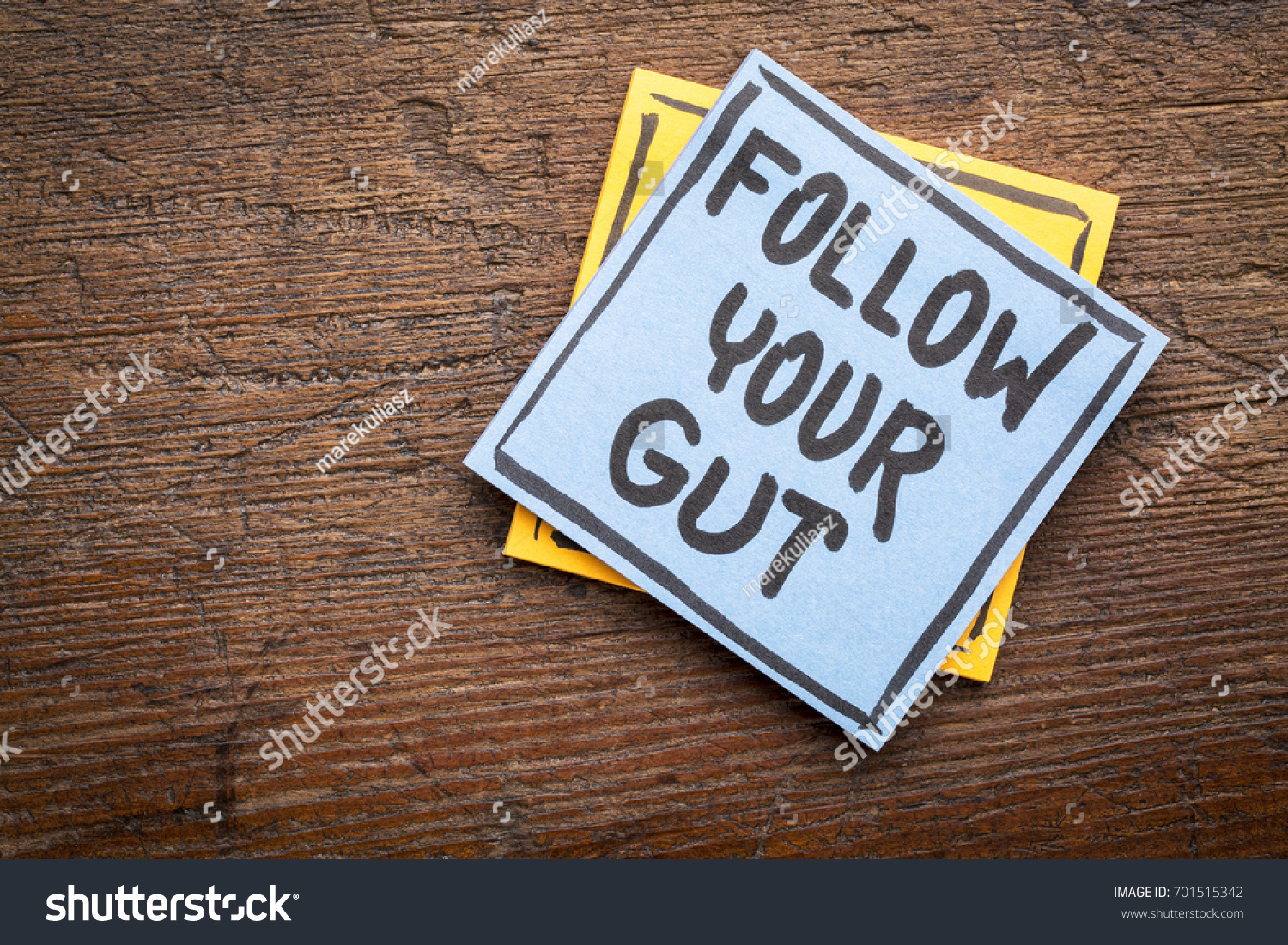 Follow your gut advice or reminder - handwriting on sticky note against rustic wood #701515342