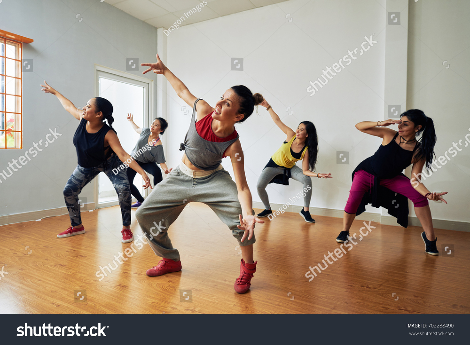 Group of energetic hip-hop dancers focused on training while gathered together in spacious dance hall #702288490