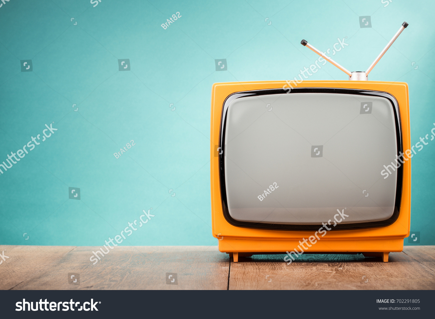 Retro old orange TV receiver on table front gradient aquamarine wall background. Vintage style filtered photo #702291805