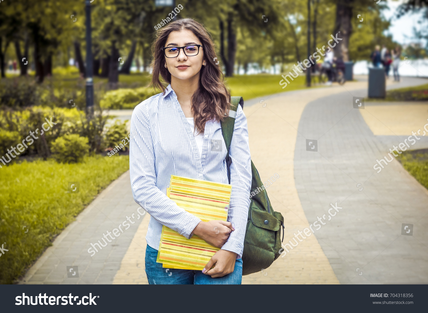 Attractive girl in the park. Indian woman in glasses with books #704318356