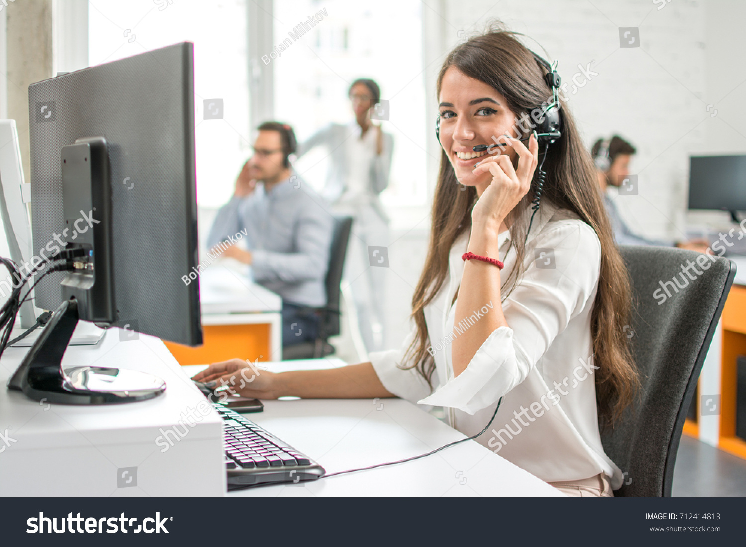 Young friendly operator woman agent with headsets working in a call centre. #712414813