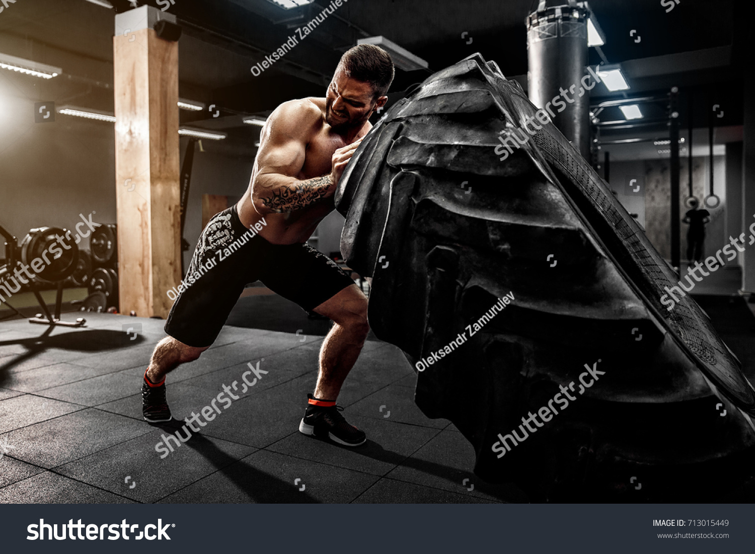 Shirtless man flipping heavy tire at gym #713015449