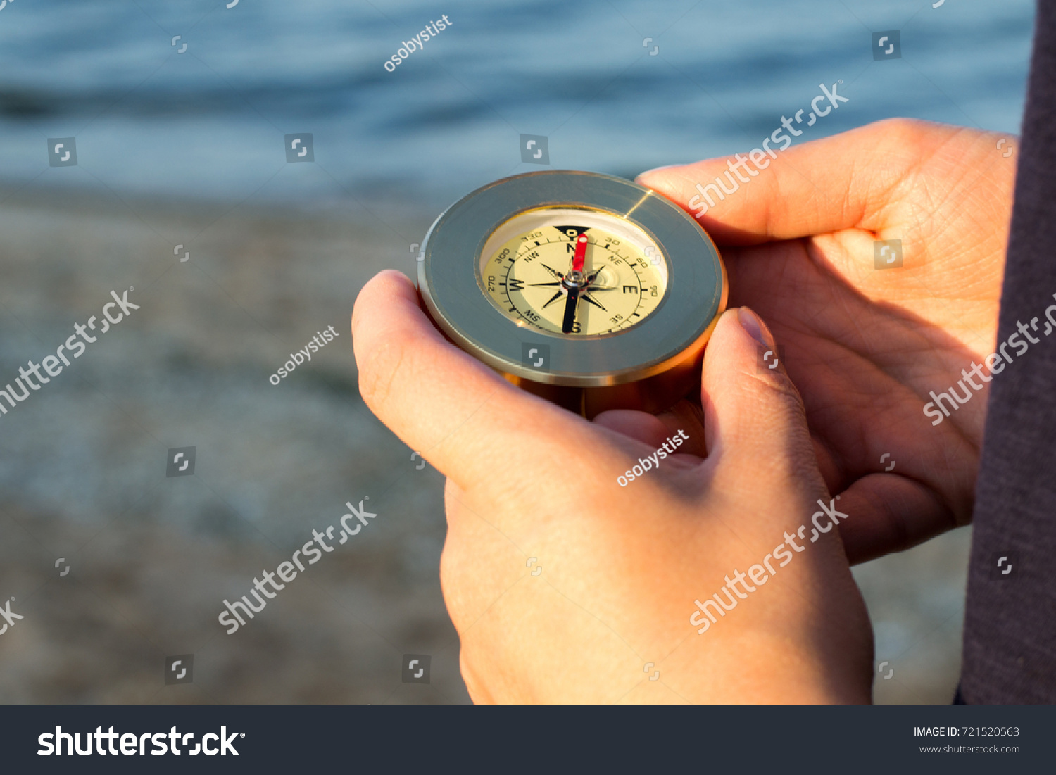 Hands holds a compass indicating the direction of the background of the sea #721520563