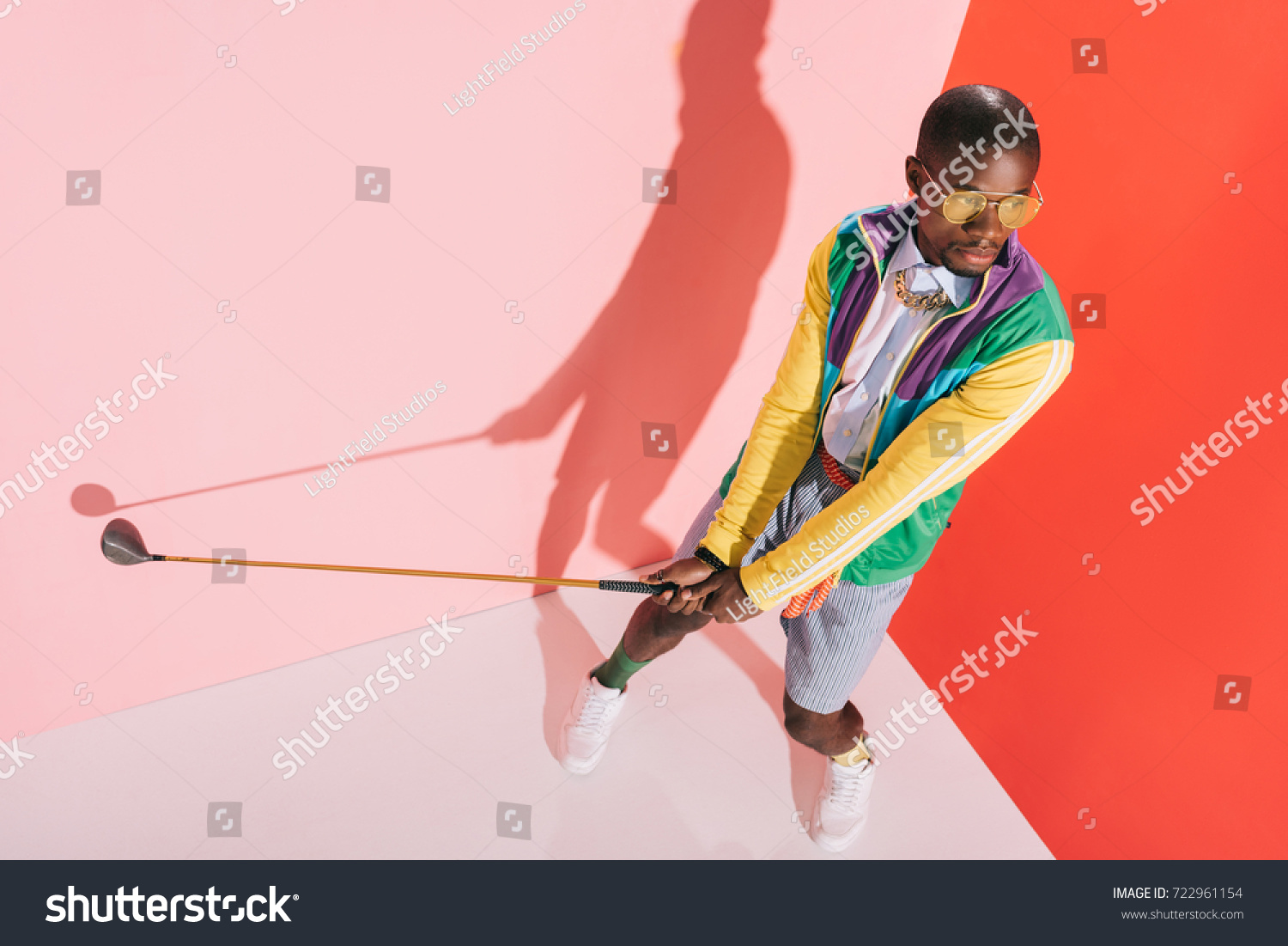 high angle view of fashionable african american man in sunglasses playing golf in studio #722961154