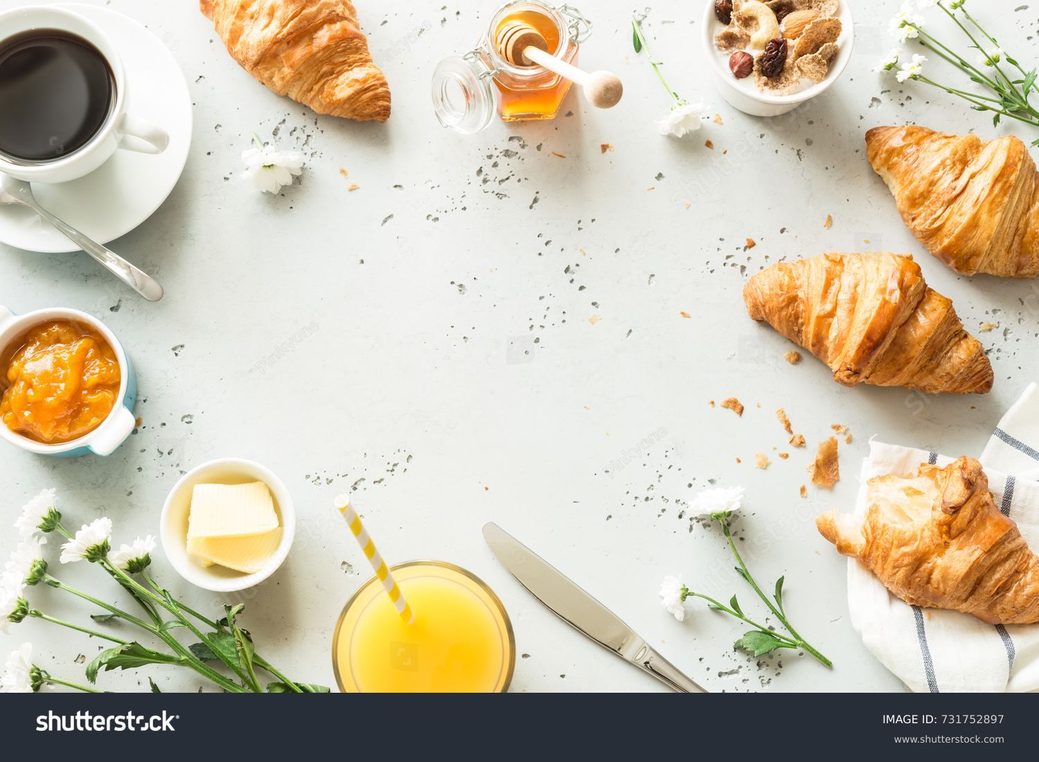Continental breakfast captured from above (top view, flat lay). Coffee, orange juice, croissants, jam, honey and flowers. Grey stone worktop as background. Layout with free text (copy) space. #731752897