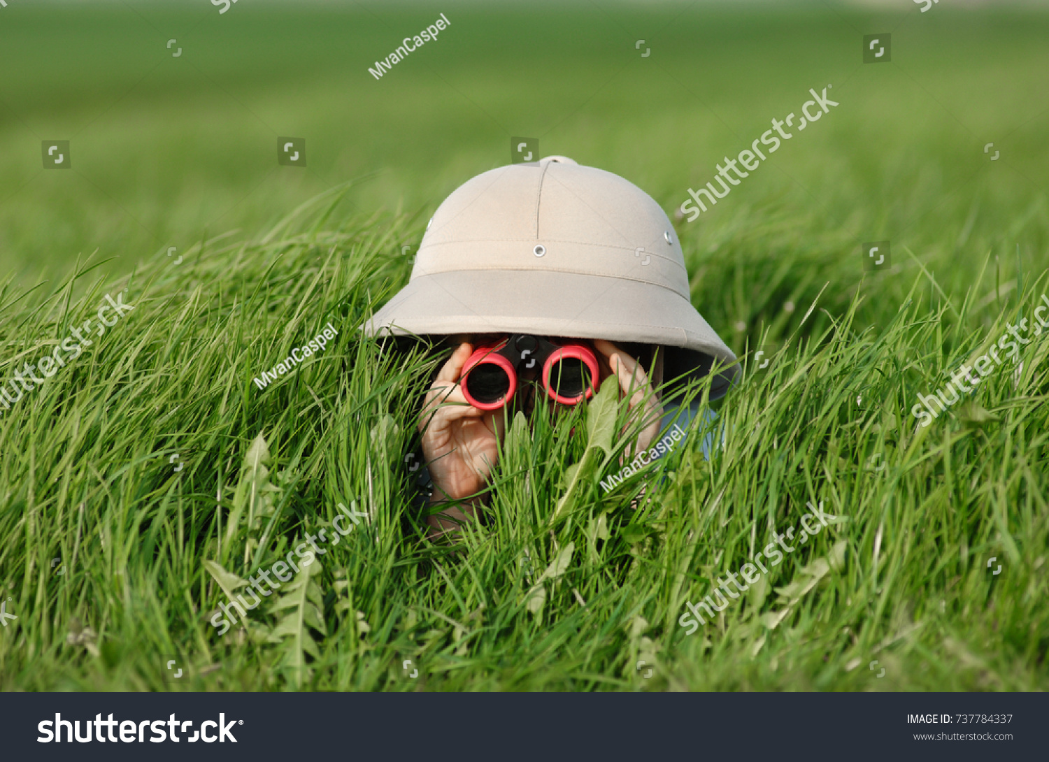 Little Boy with Binoculars and safari Hat, laying in the grass searching for Knowledge #737784337