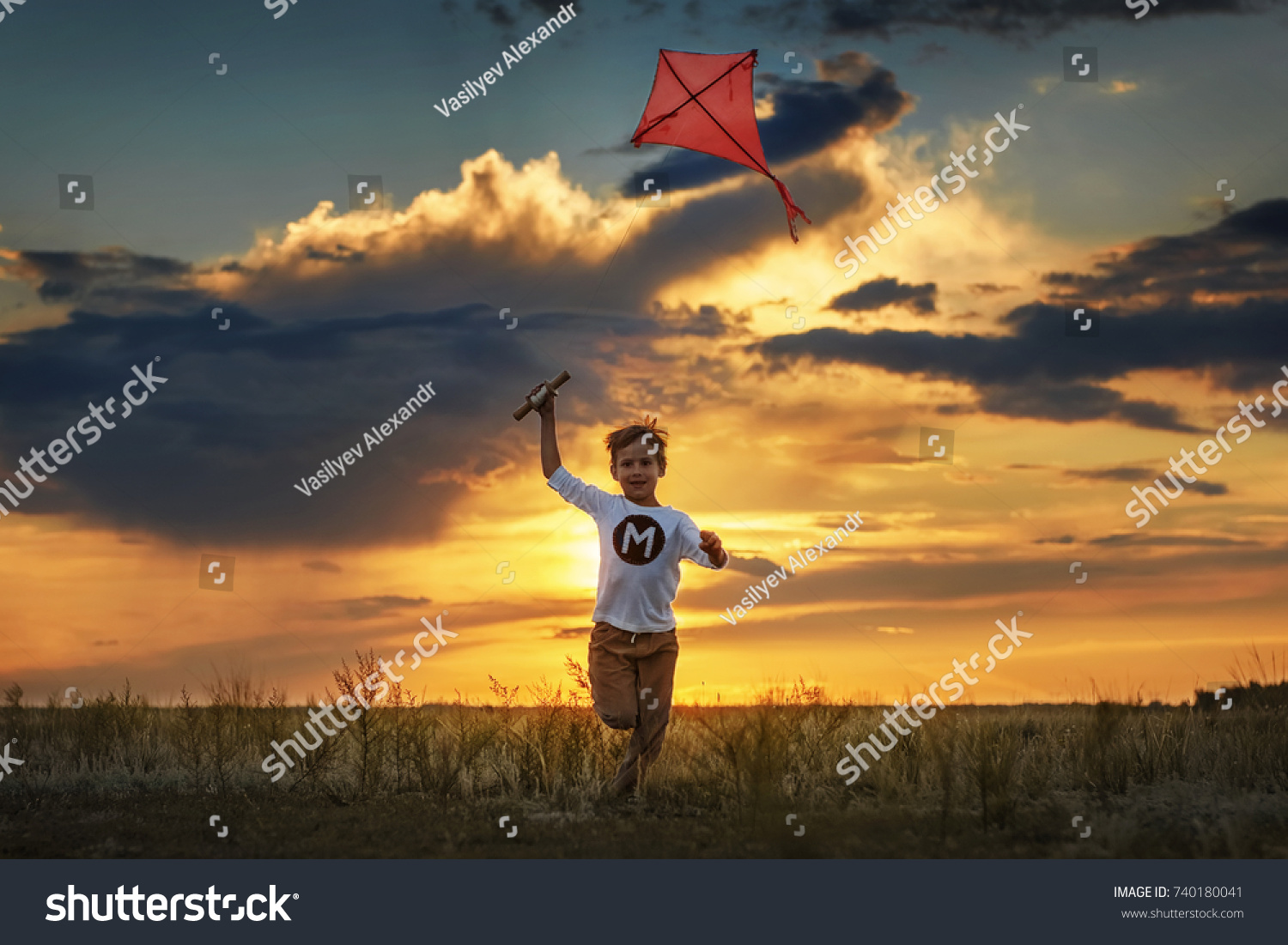 Boy launch a kite in the field at sunset #740180041